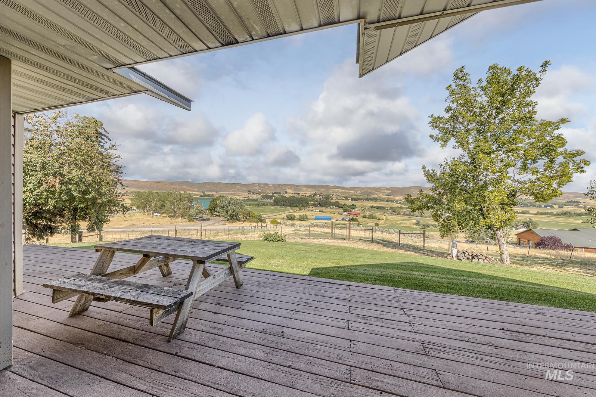 Wooden terrace featuring a view of countryside and outdoor dining space