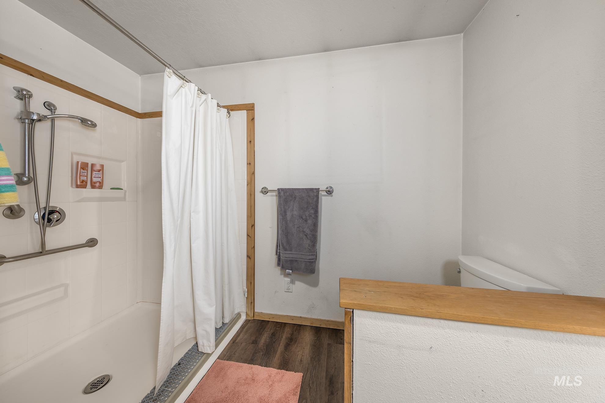 Bathroom featuring wood finished floors and curtained shower