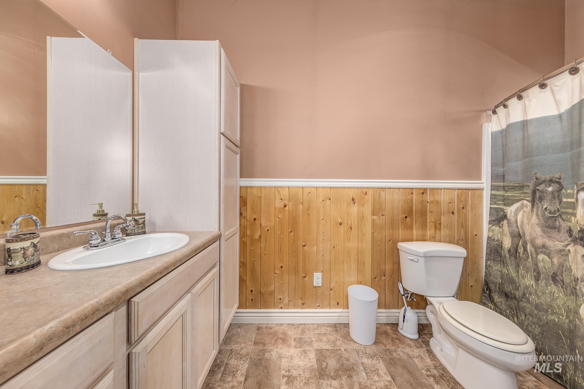 Full bath featuring wooden walls, a wainscoted wall, and vanity