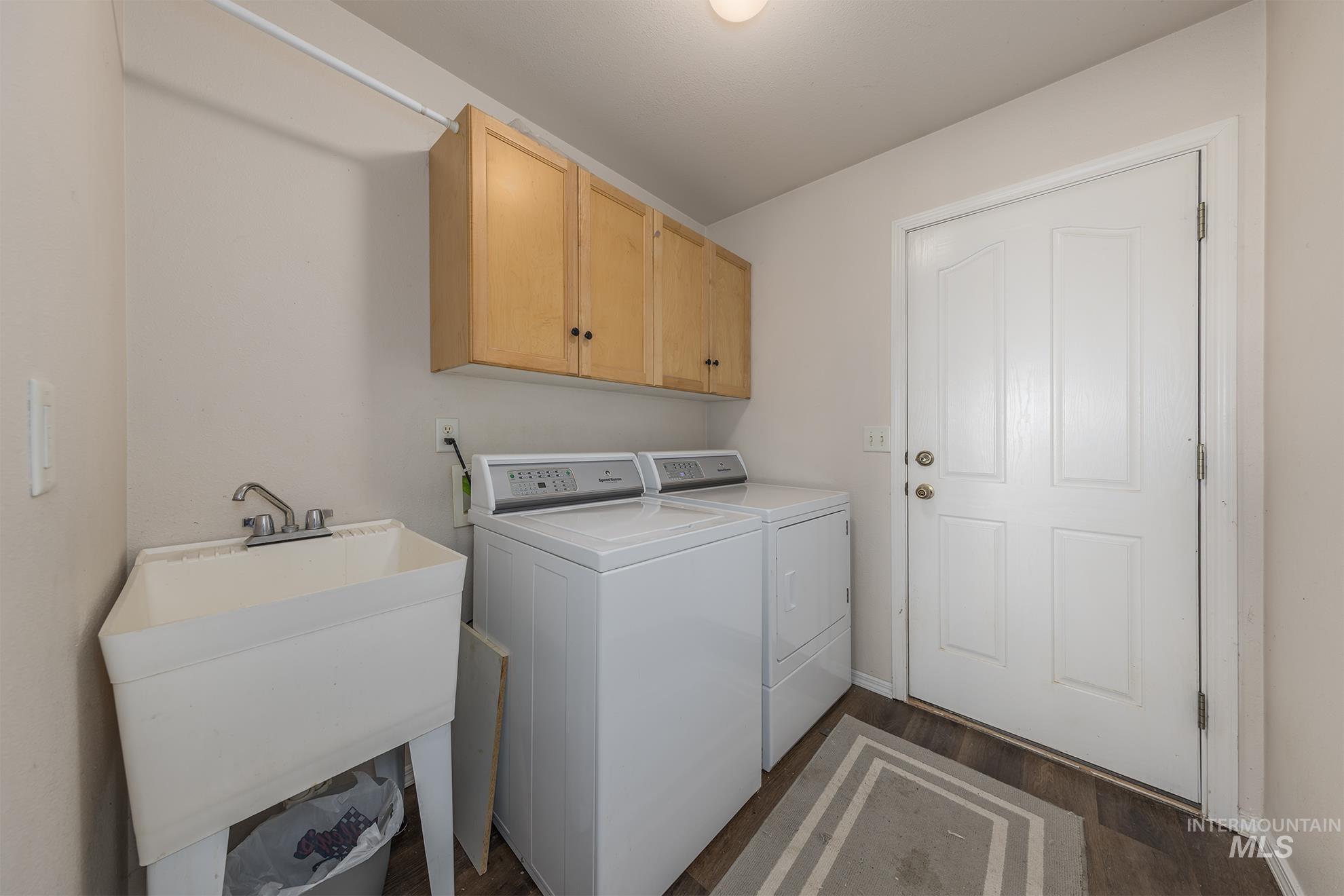 Washroom with washer and clothes dryer, cabinet space, and dark wood-type flooring