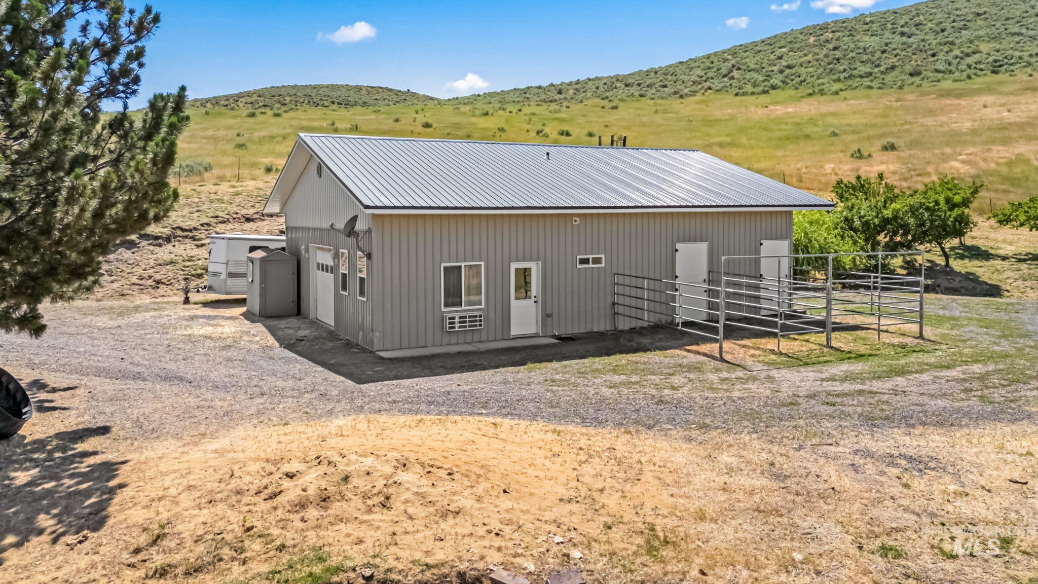 Rear view of property featuring a metal roof, a mountain view, an exterior structure, and a view of countryside