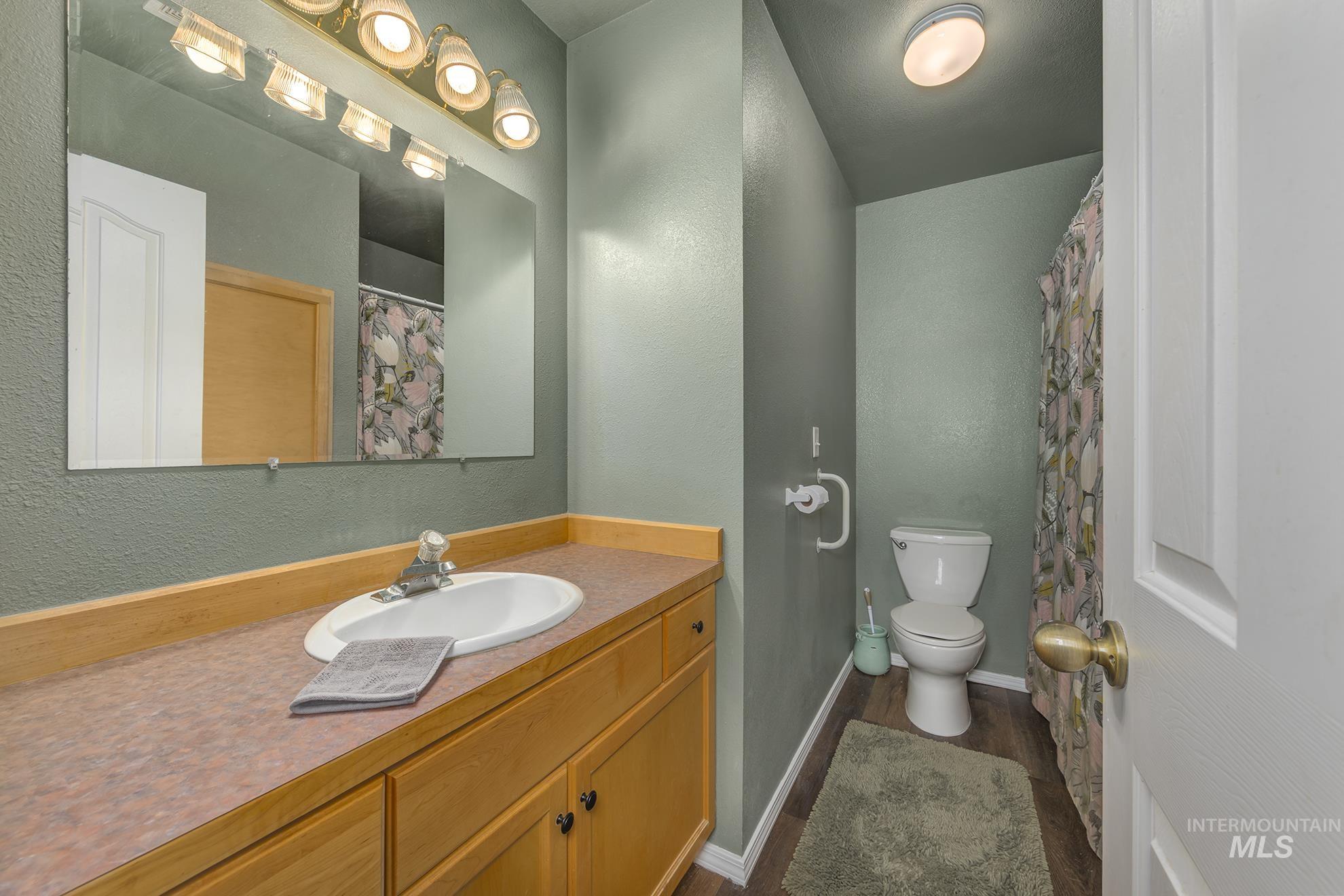 Bathroom with a textured wall, vanity, and wood finished floors