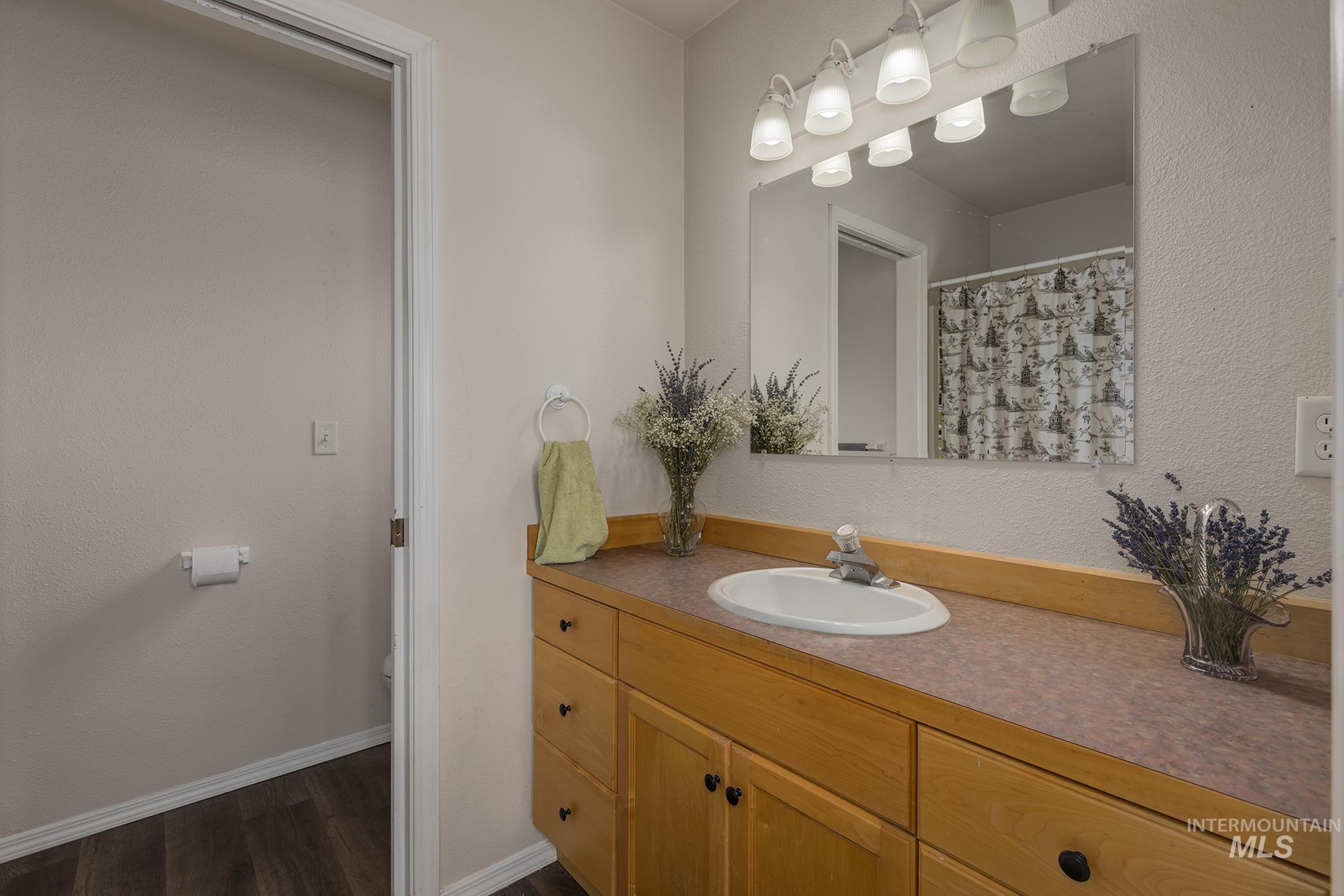 Bathroom with vanity, wood finished floors, and a textured wall