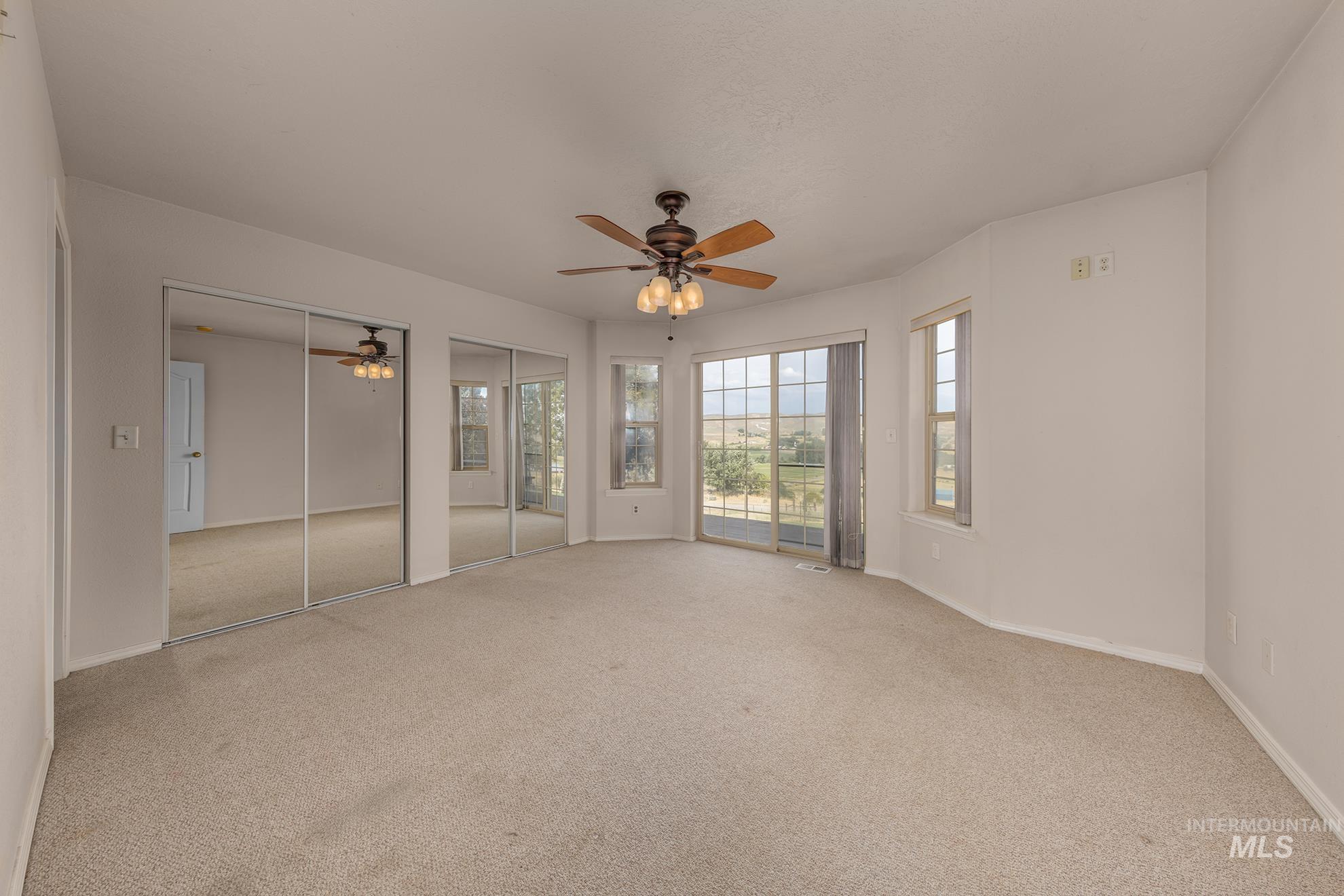 Unfurnished bedroom with two closets, carpet floors, and a ceiling fan