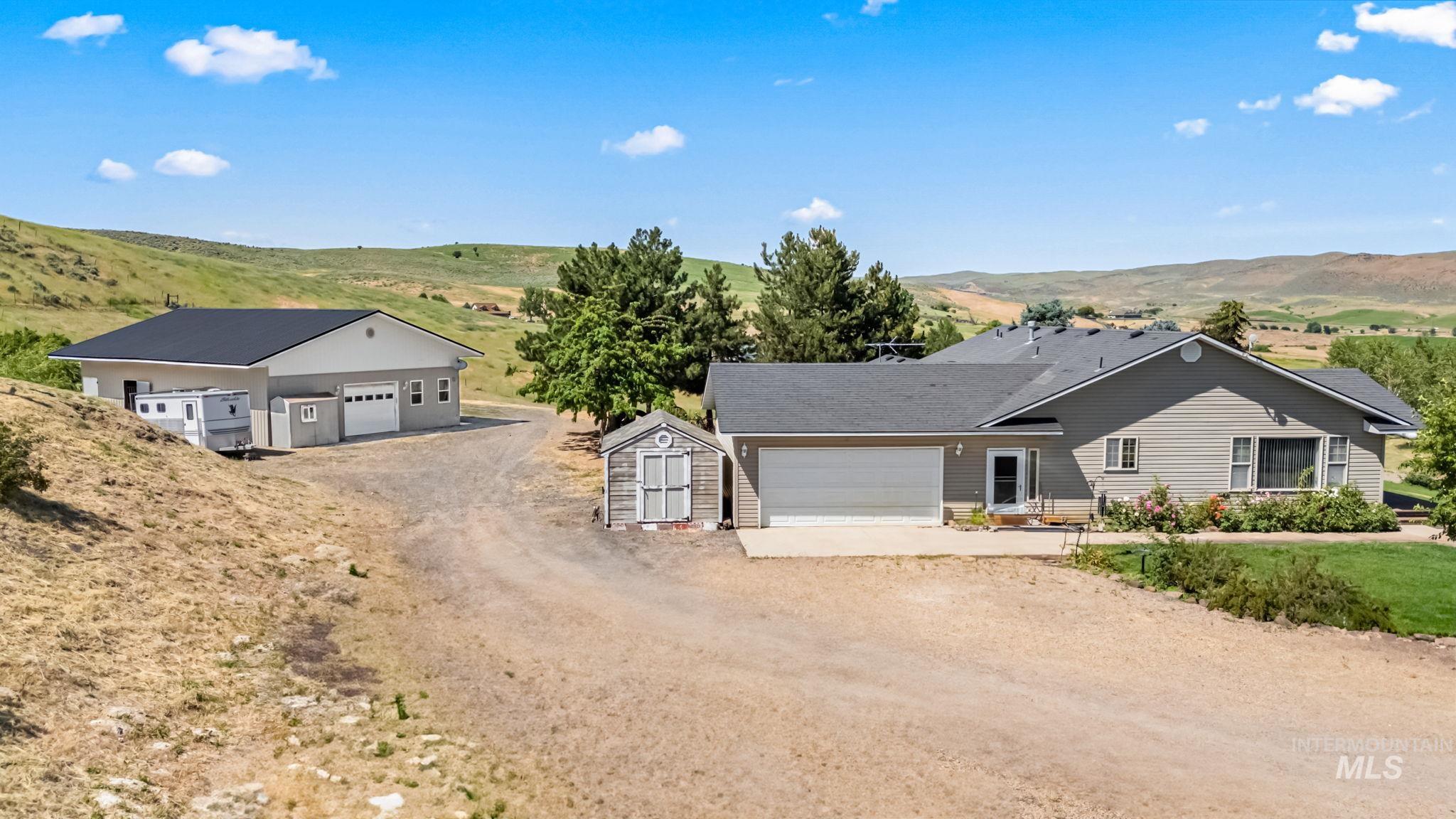 Ranch-style house featuring driveway, a garage, a storage unit, and a mountain view