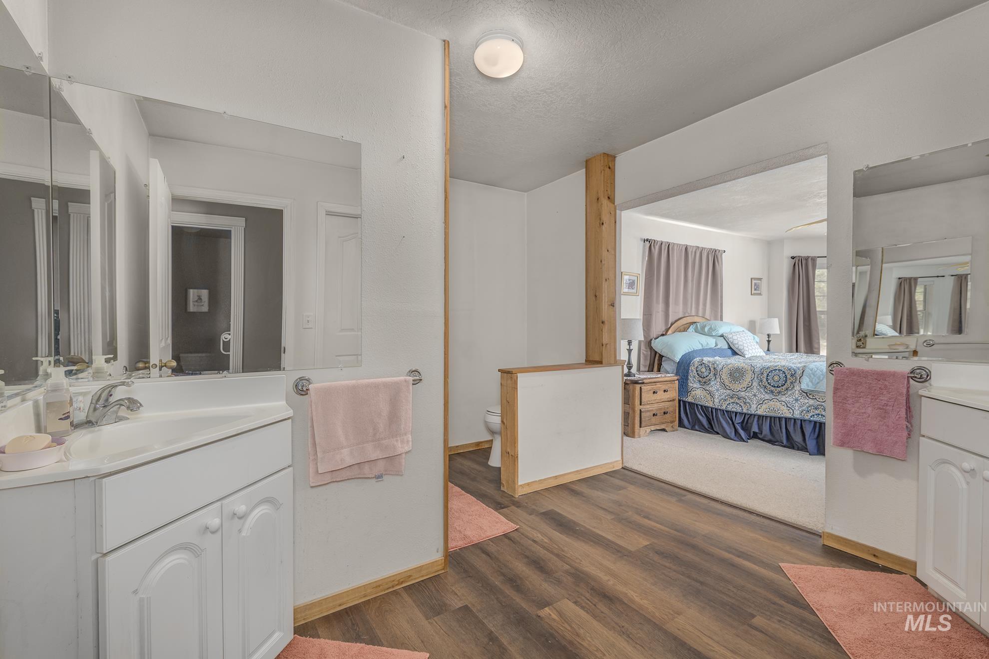 Ensuite bathroom with vanity, wood finished floors, and a textured ceiling