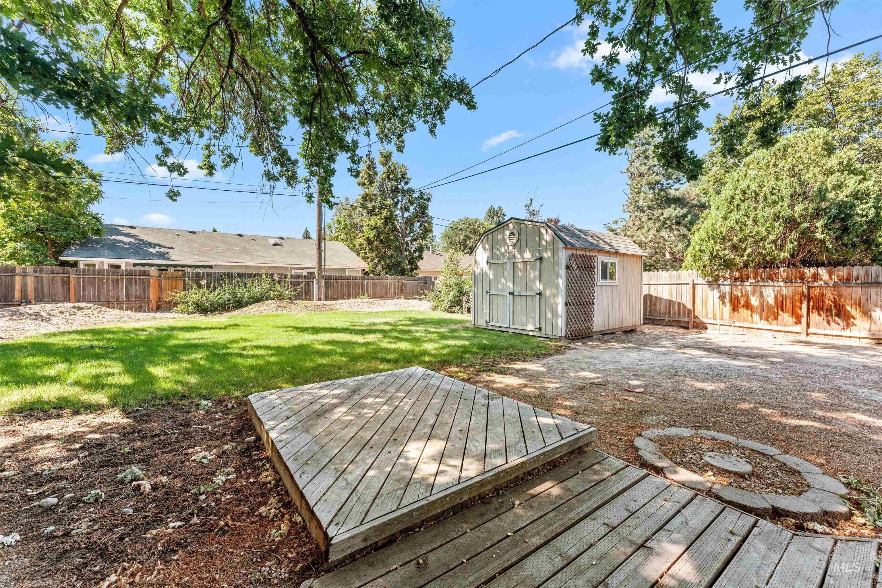 Wooden deck with a fenced backyard, a patio area, and a storage shed