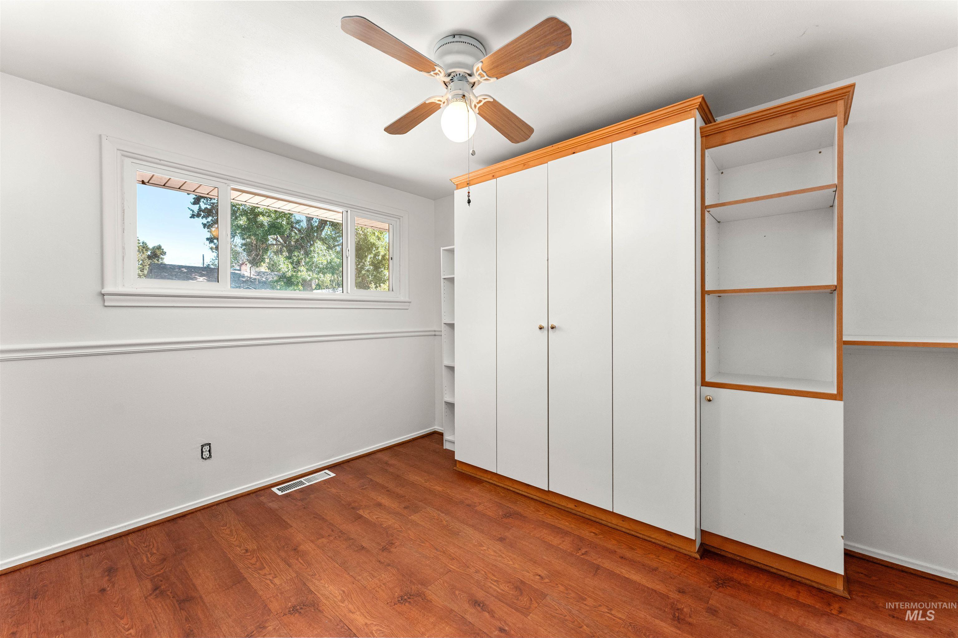 Unfurnished bedroom with dark wood finished floors, a closet, and a ceiling fan