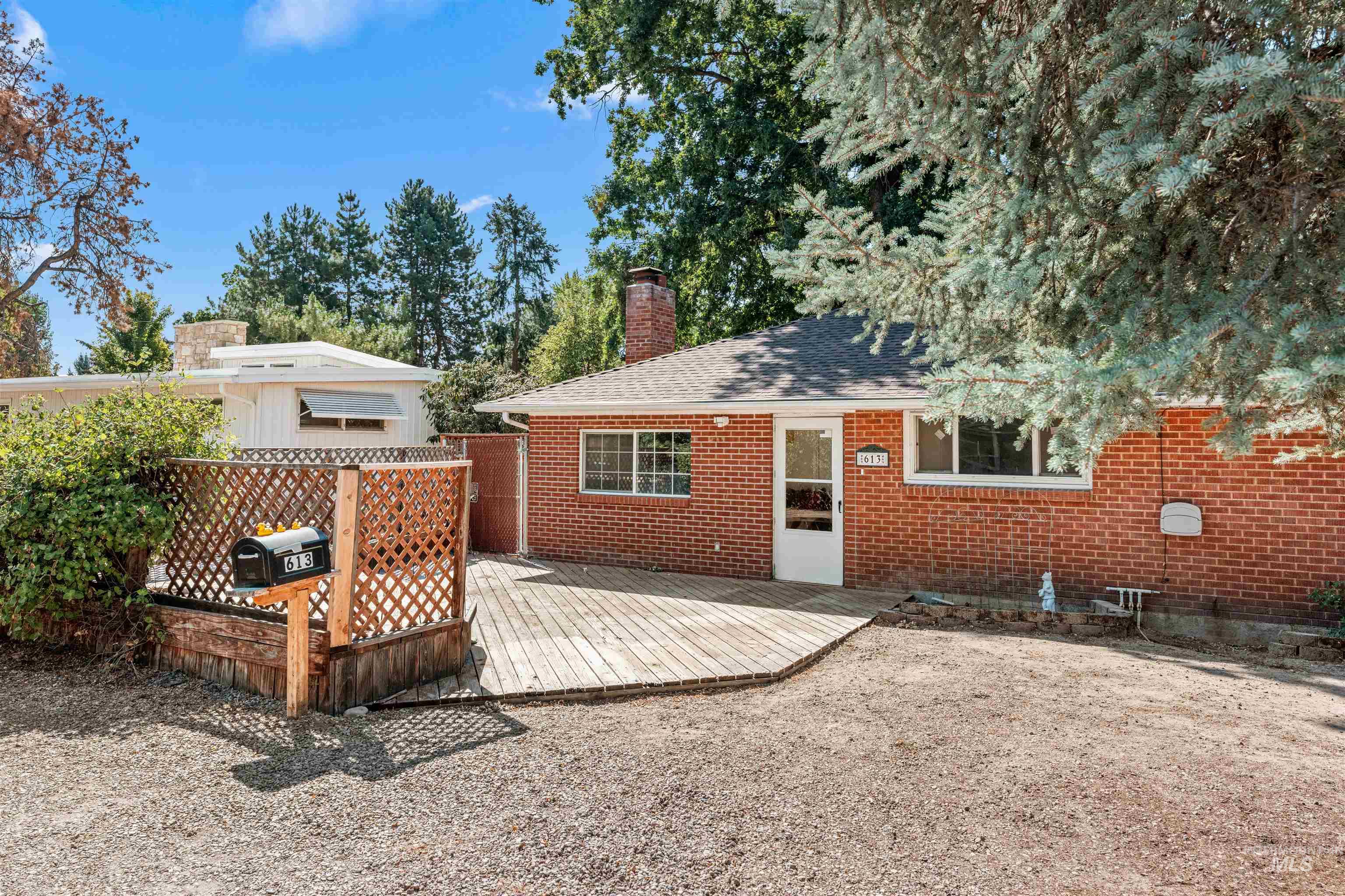 Rear view of house featuring a wooden deck, a chimney, brick siding, and a shingled roof