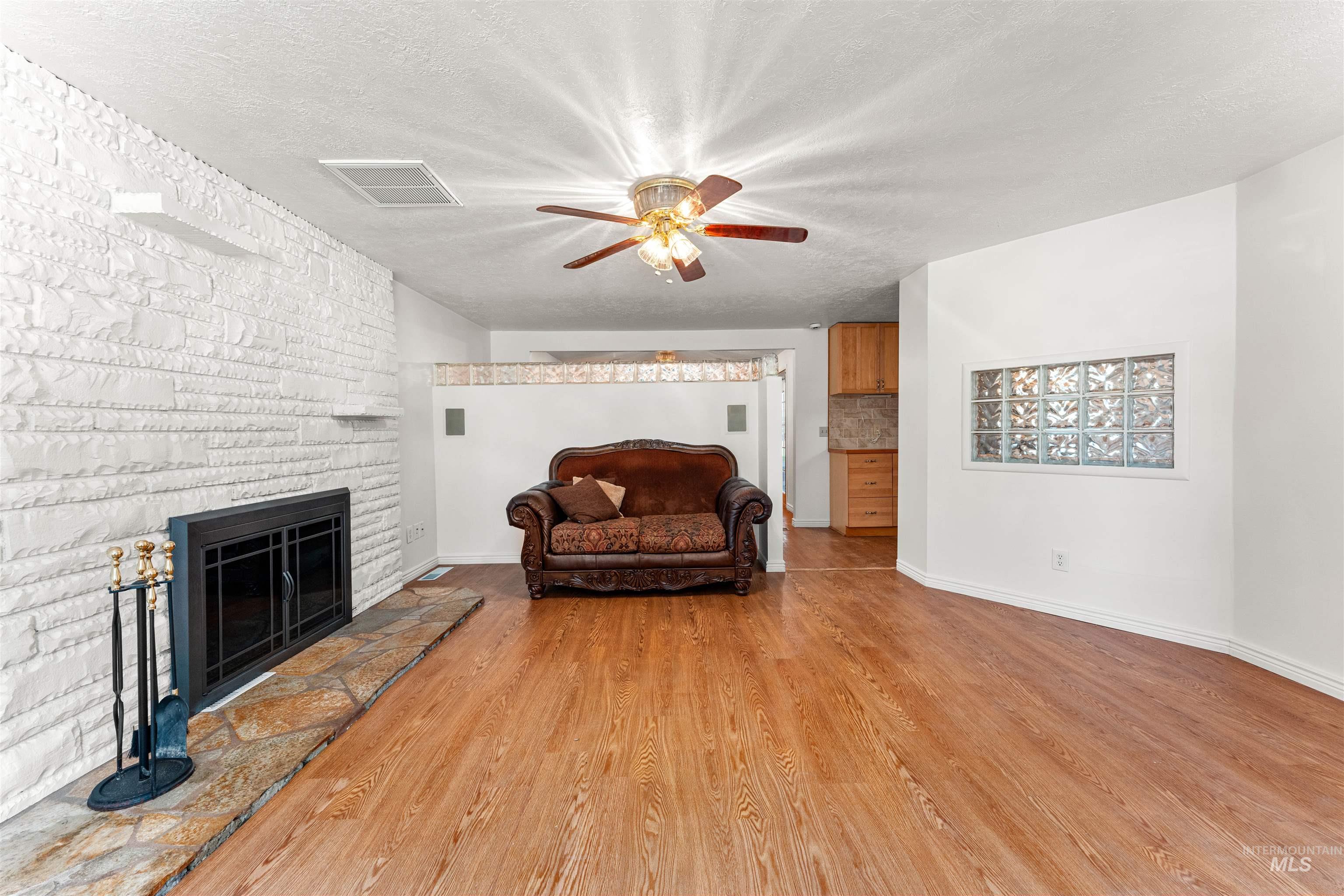 Sitting room featuring light wood finished floors, a textured ceiling, a fireplace, and ceiling fan