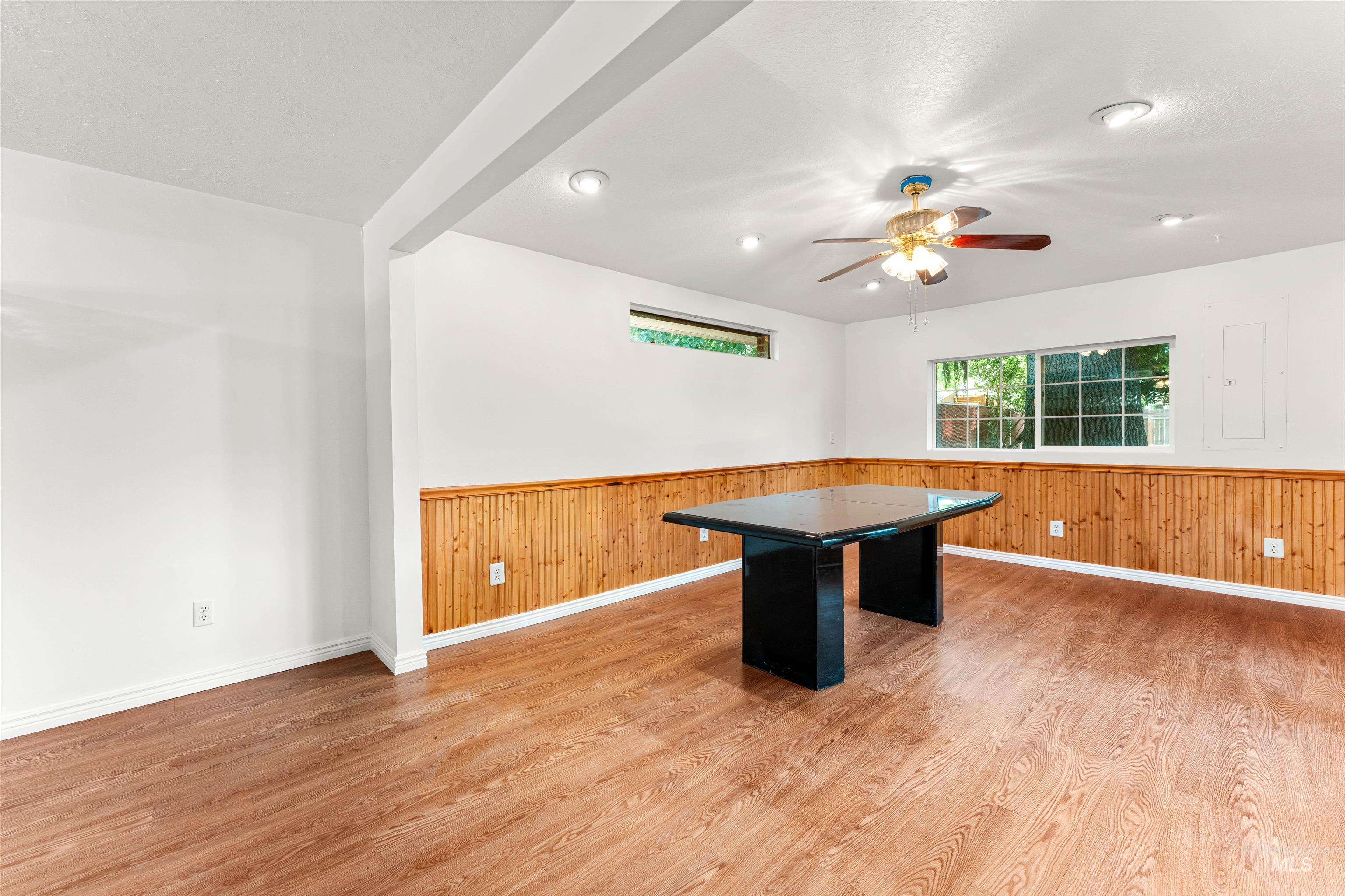 Playroom with light wood-style floors, a ceiling fan, wood walls, wainscoting, and beamed ceiling