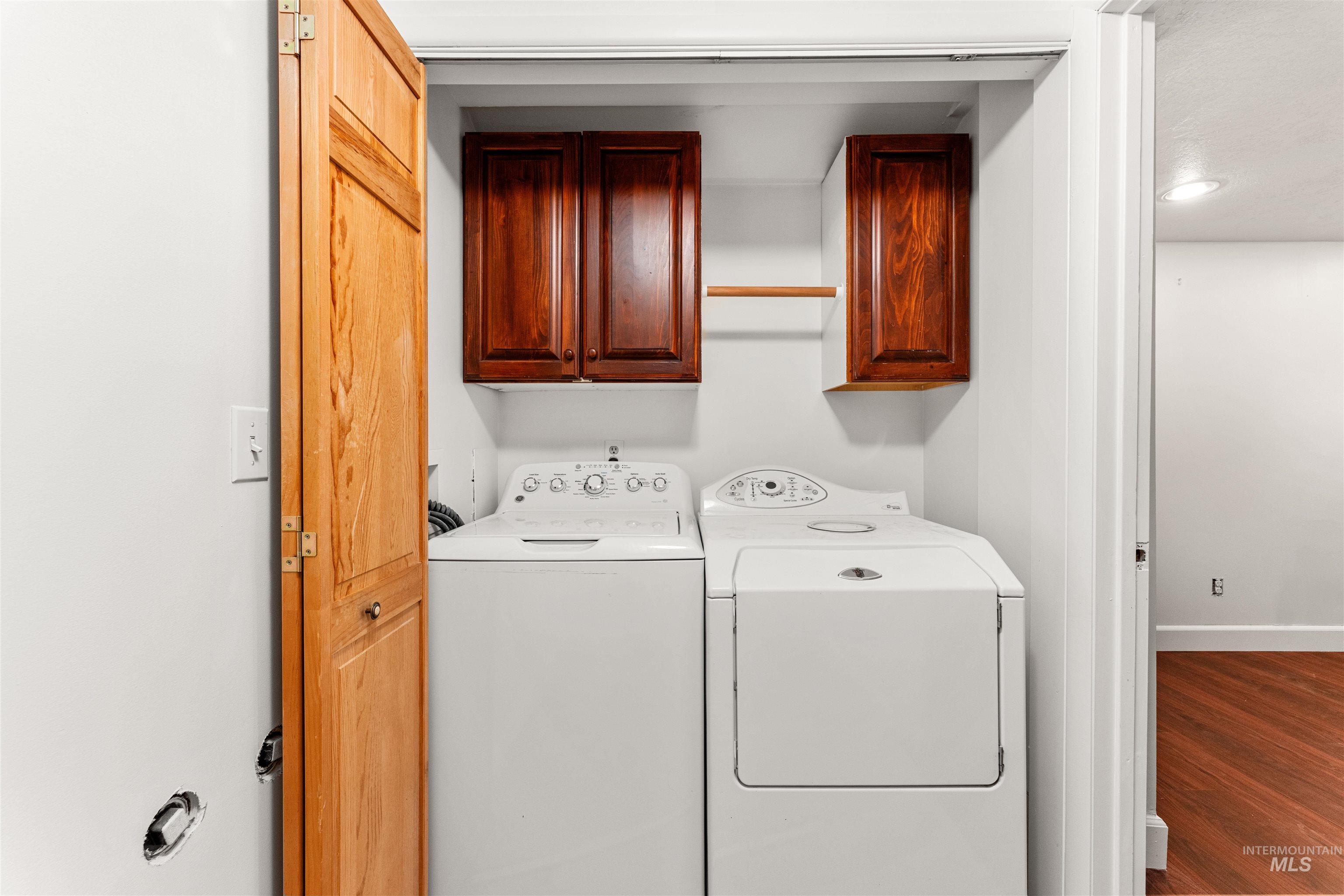 Washroom featuring cabinet space, wood finished floors, washing machine and clothes dryer, and recessed lighting