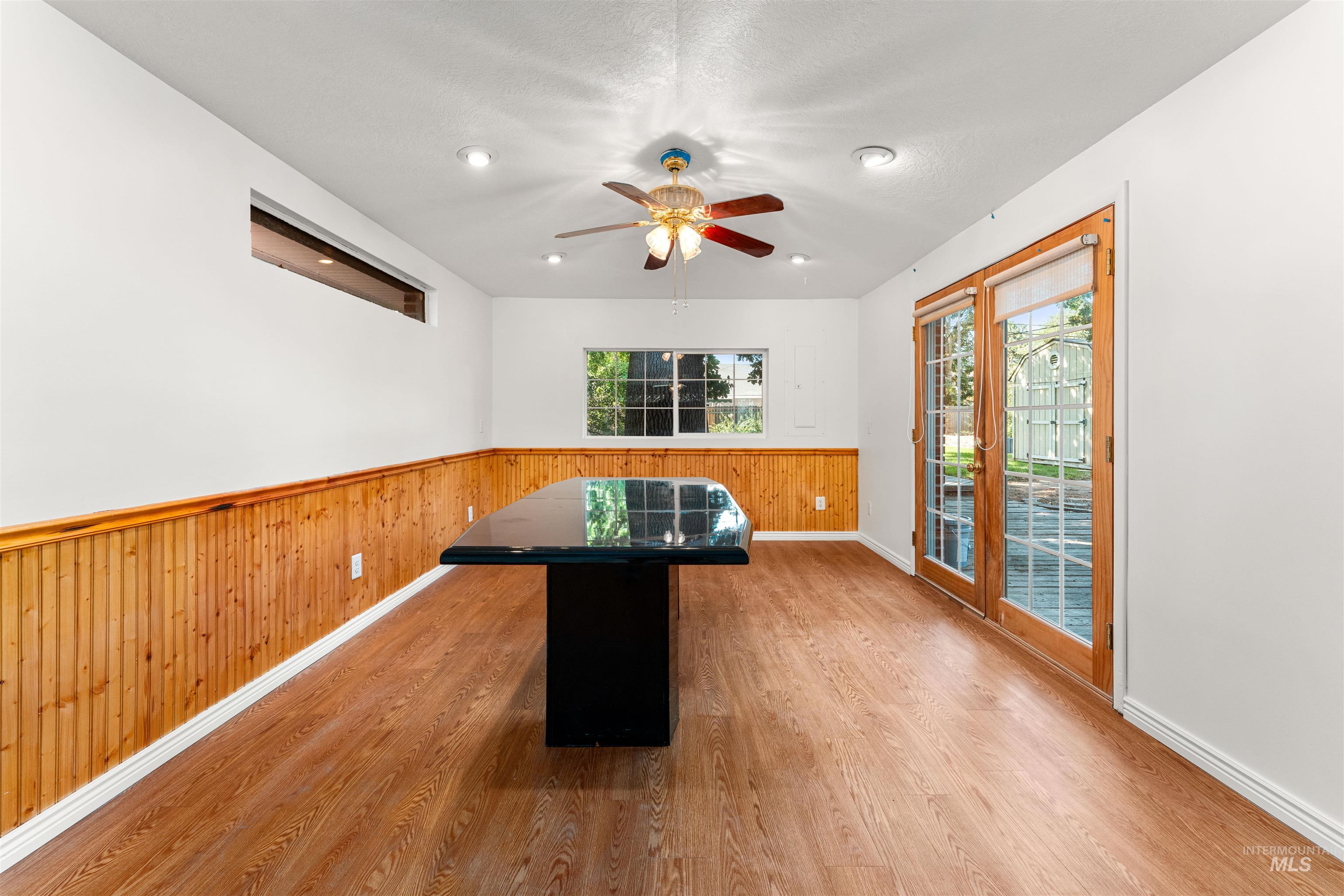 Unfurnished dining area featuring wood walls, light wood finished floors, a wainscoted wall, a ceiling fan, and recessed lighting