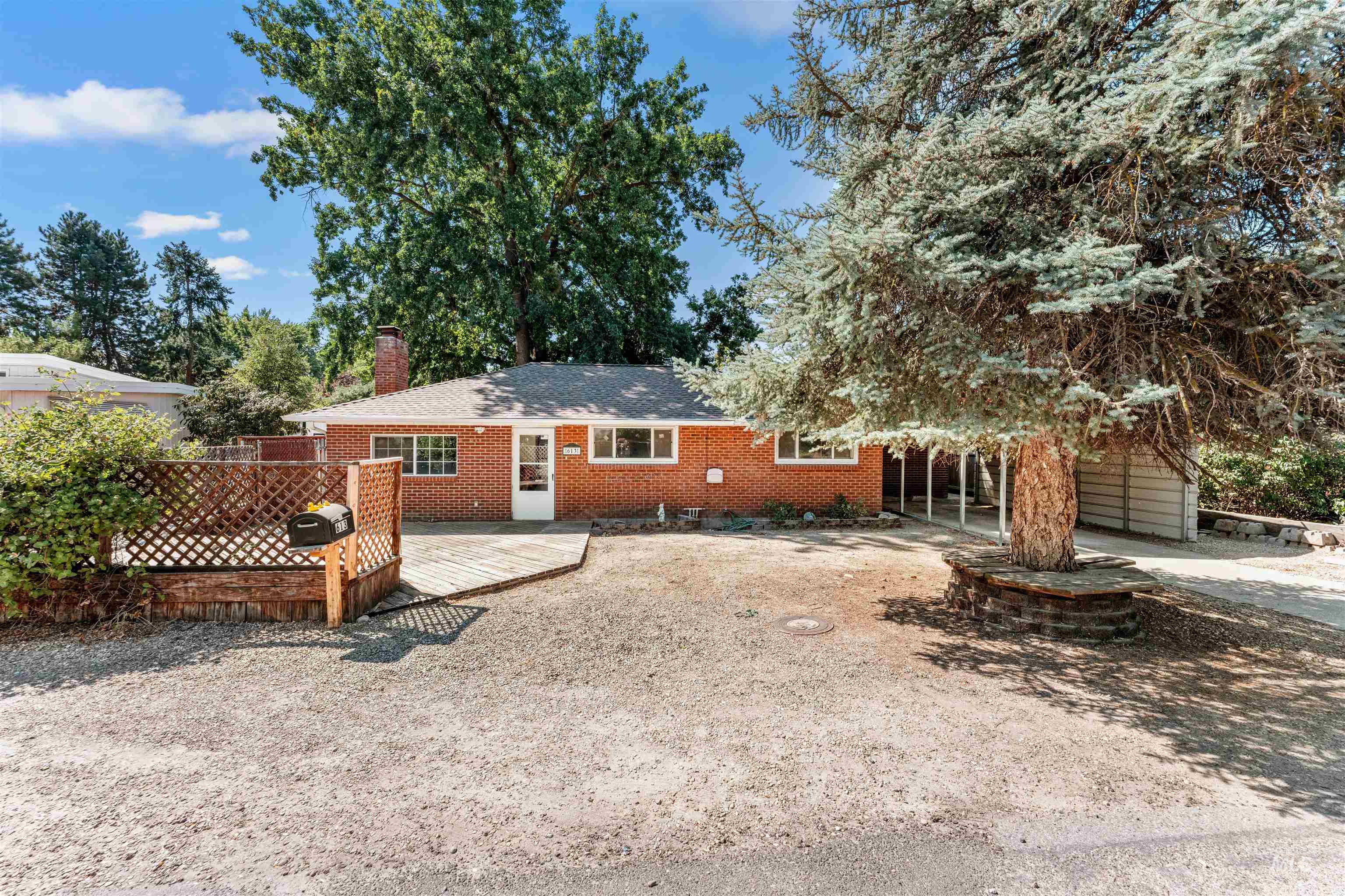 Back of property with brick siding, a chimney, a deck, and a carport