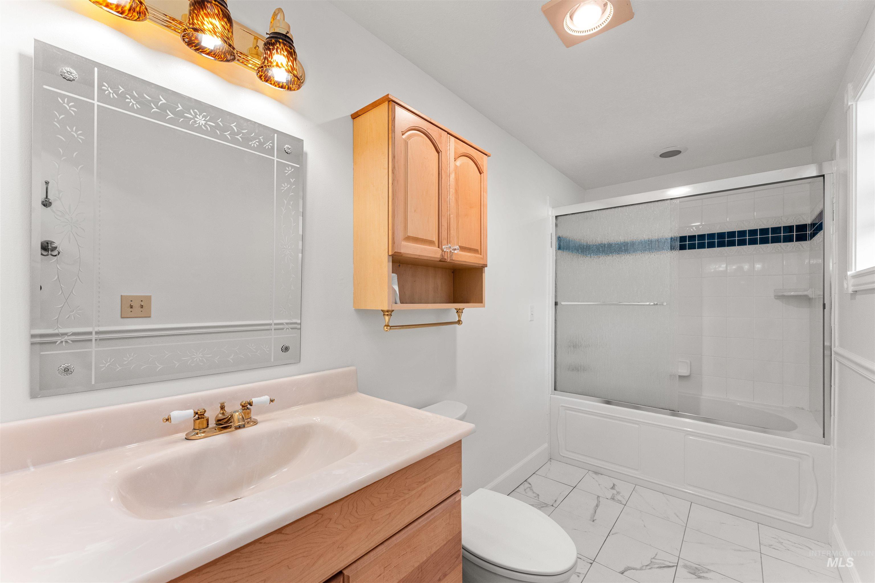 Bathroom featuring enclosed tub / shower combo, vanity, and light marble finish flooring