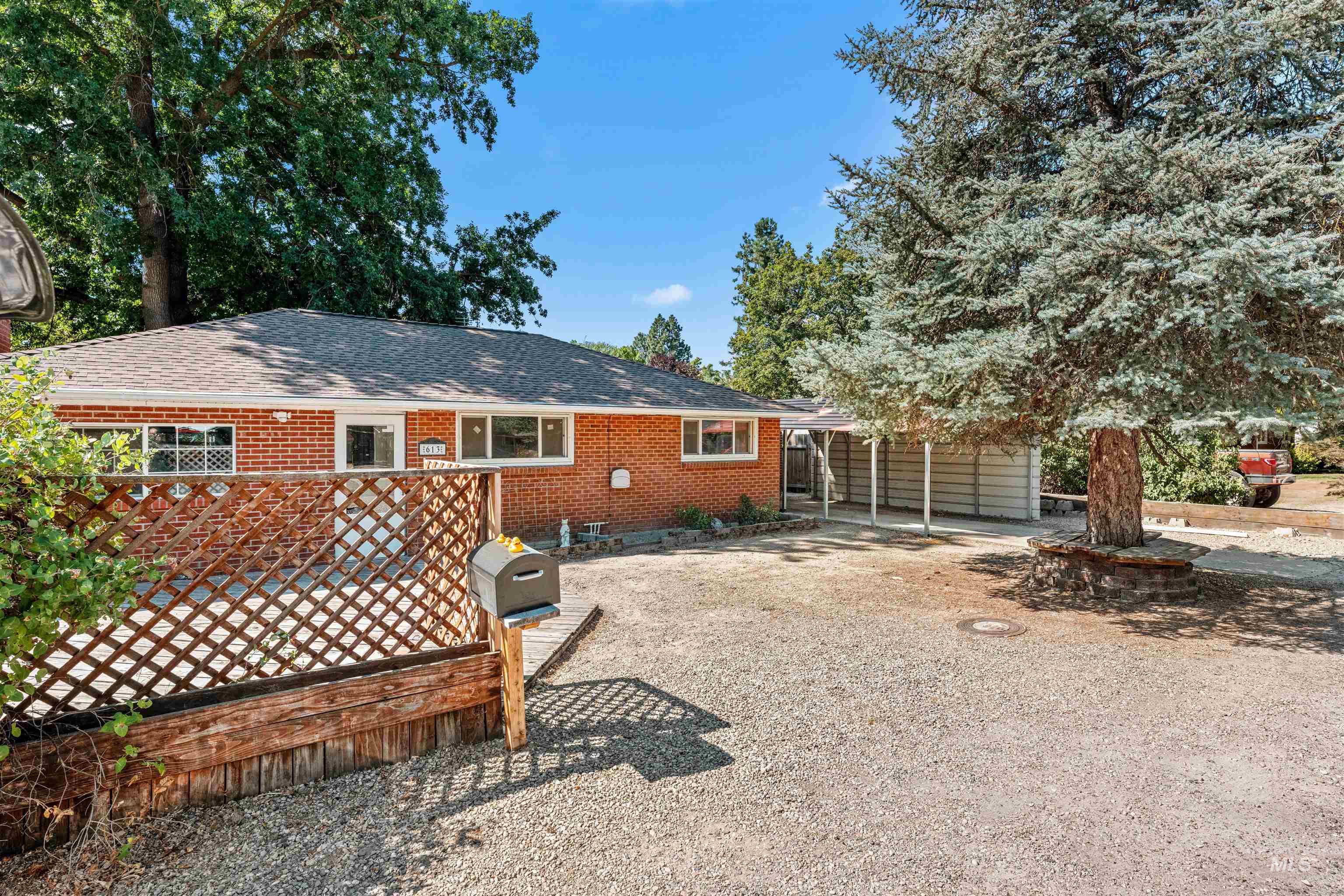 Back of property featuring gravel driveway and brick siding