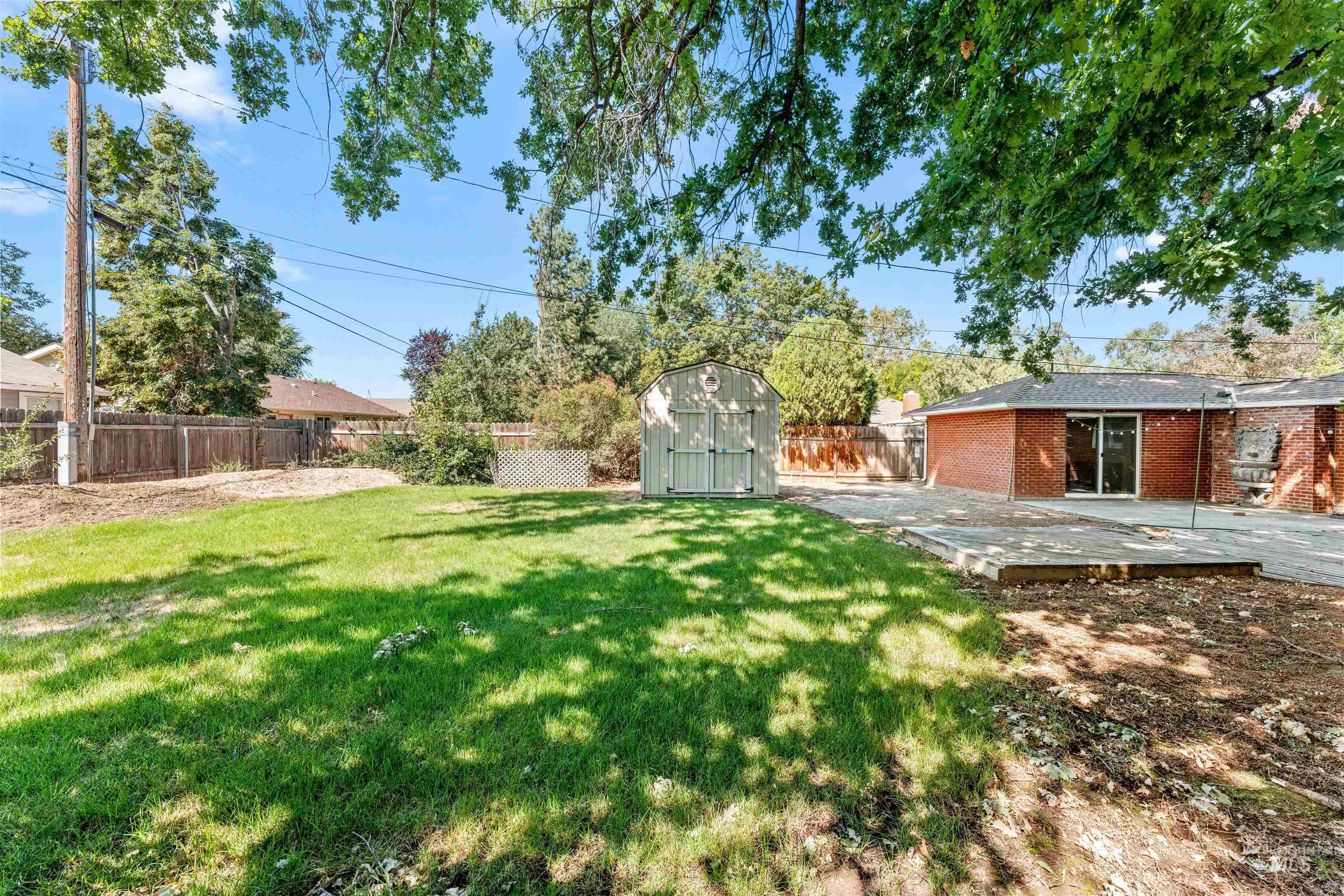 Fenced backyard featuring a storage shed and a patio