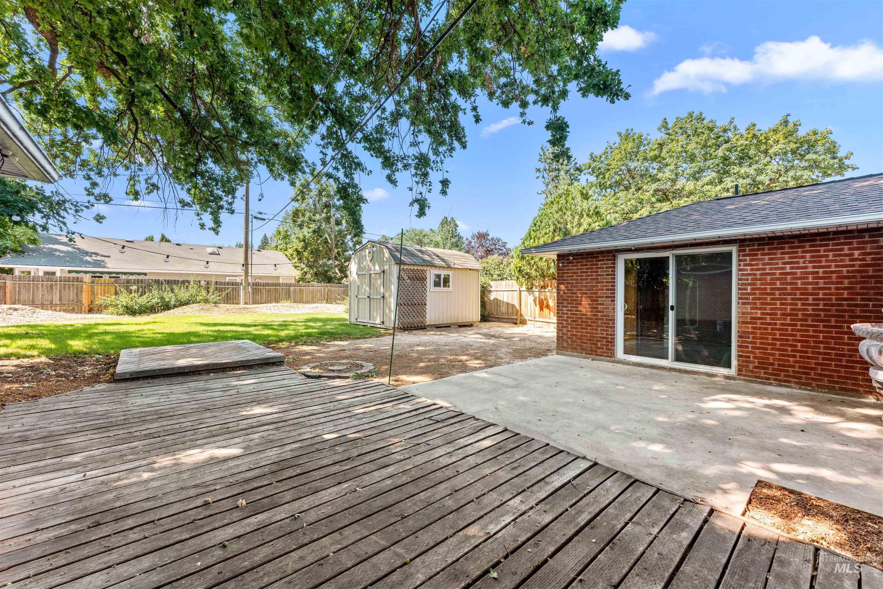 Wooden deck featuring a patio, a fenced backyard, and a storage shed
