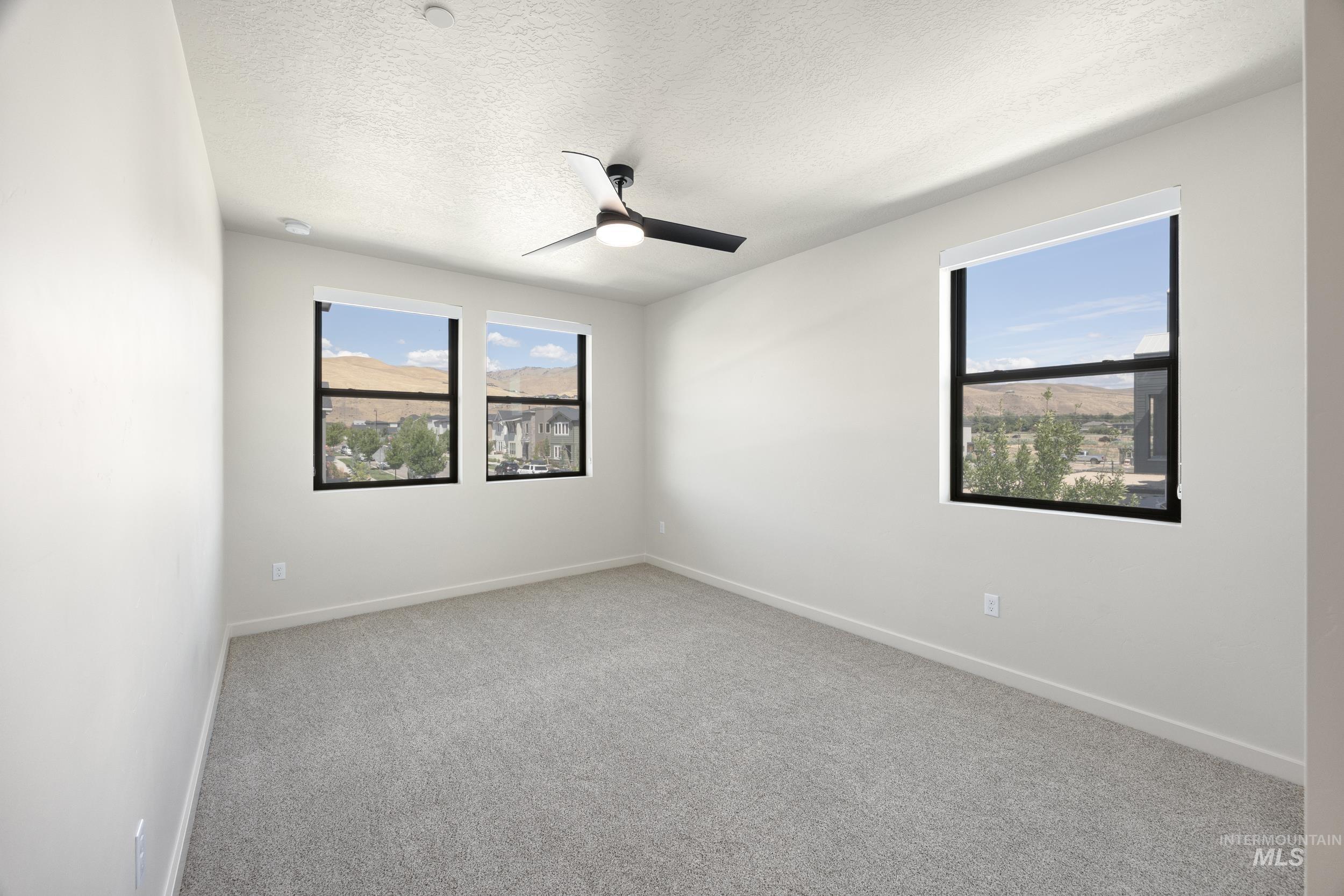 Unfurnished room with light carpet, a ceiling fan, and a textured ceiling