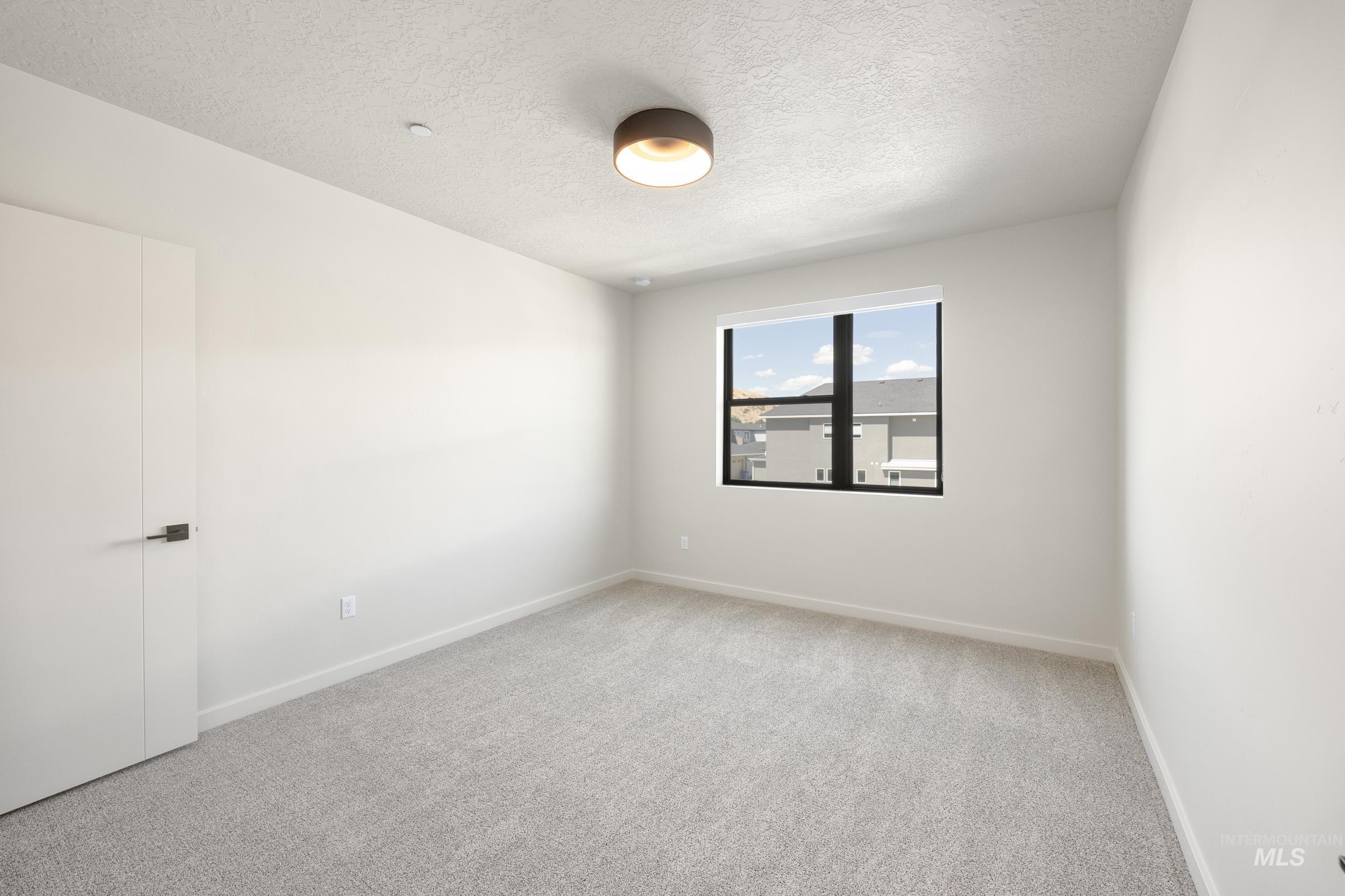 Empty room featuring light carpet and a textured ceiling
