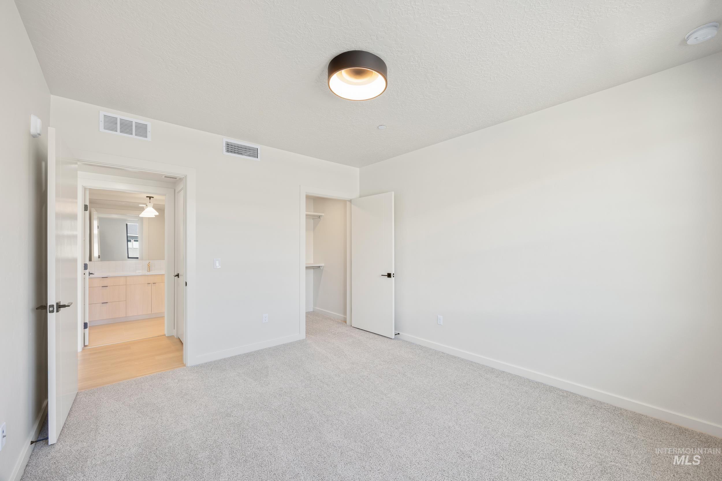 Unfurnished bedroom featuring carpet floors, a spacious closet, and a textured ceiling