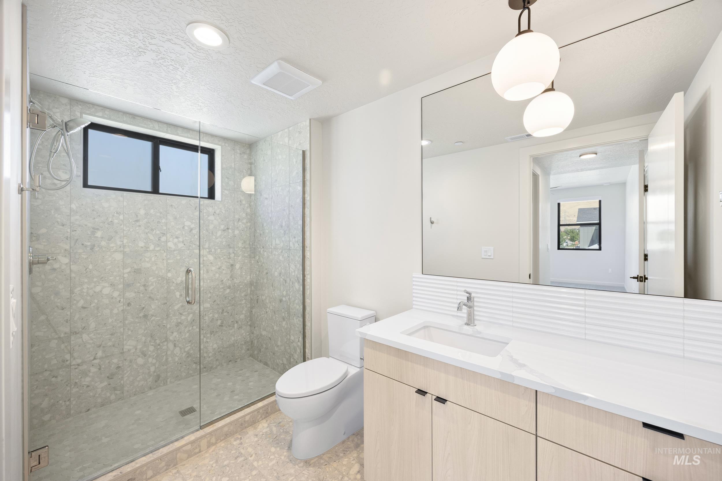 Full bath with a stall shower, vanity, a textured ceiling, and recessed lighting