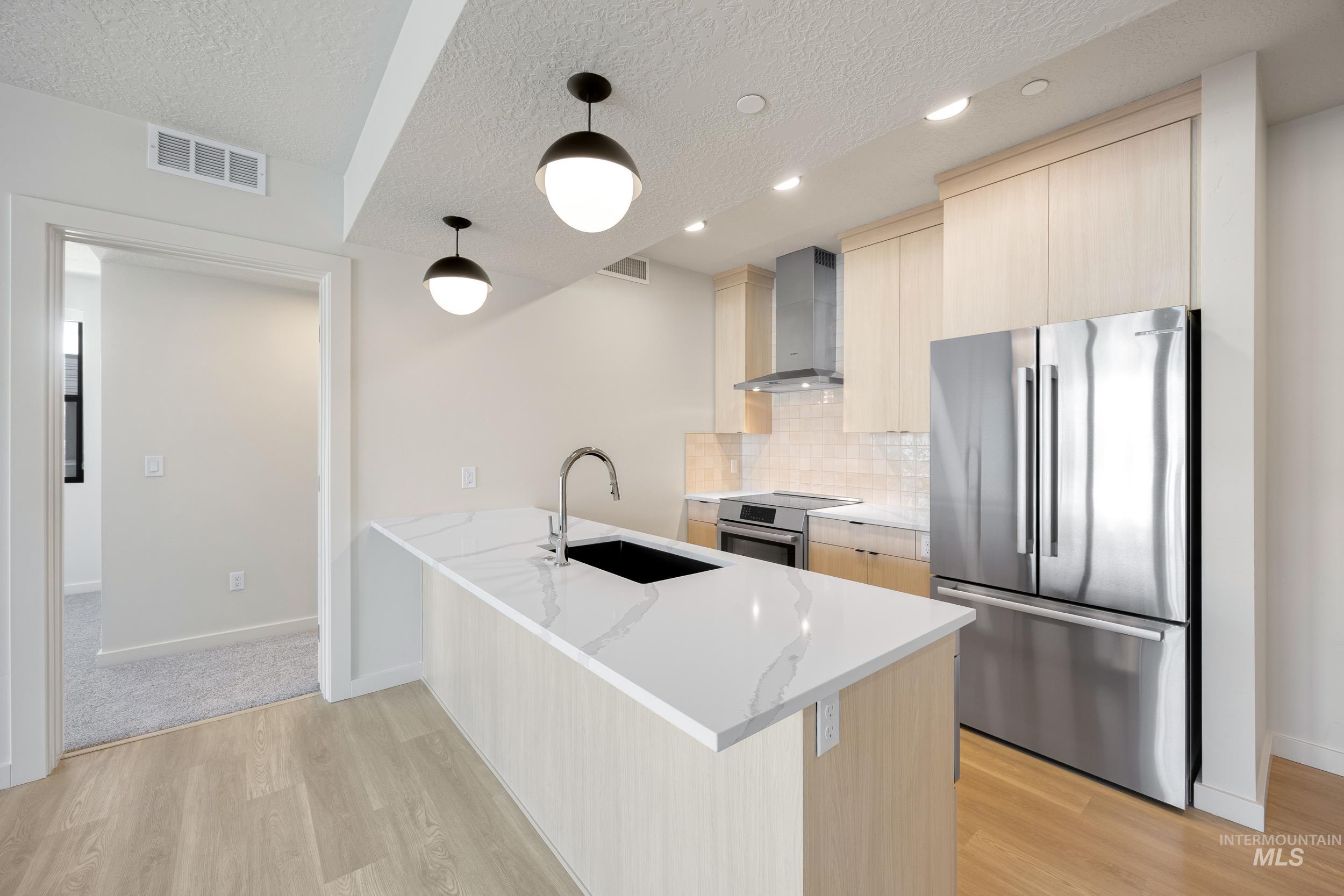 Kitchen with appliances with stainless steel finishes, decorative light fixtures, light stone counters, decorative backsplash, and modern cabinets