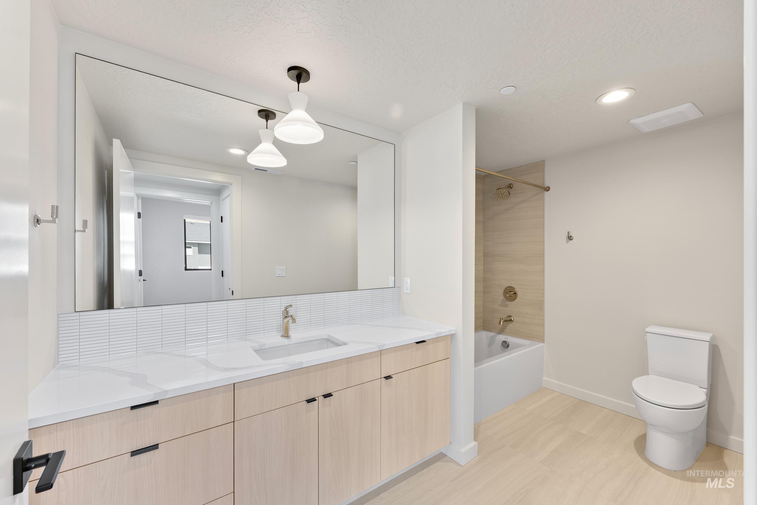 Full bathroom with washtub / shower combination, vanity, and recessed lighting