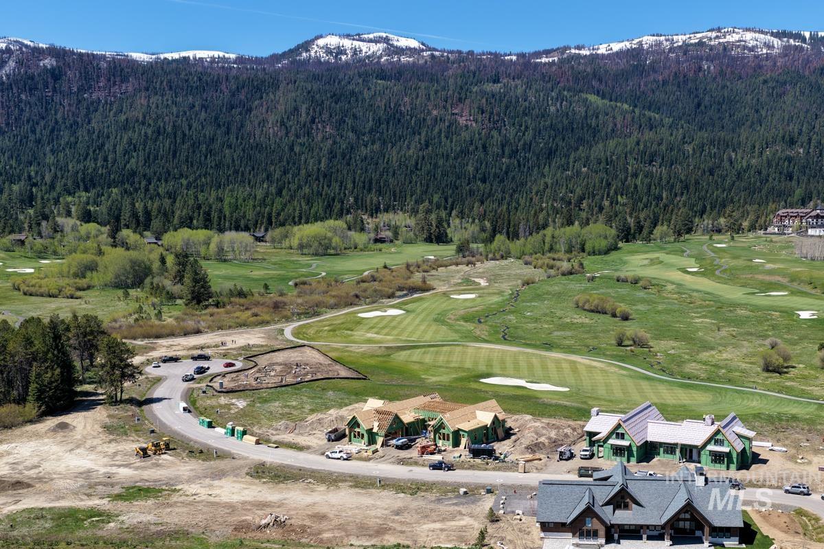 Expansive mountain landscape featuring a golf course, mature trees, and snow-capped peaks