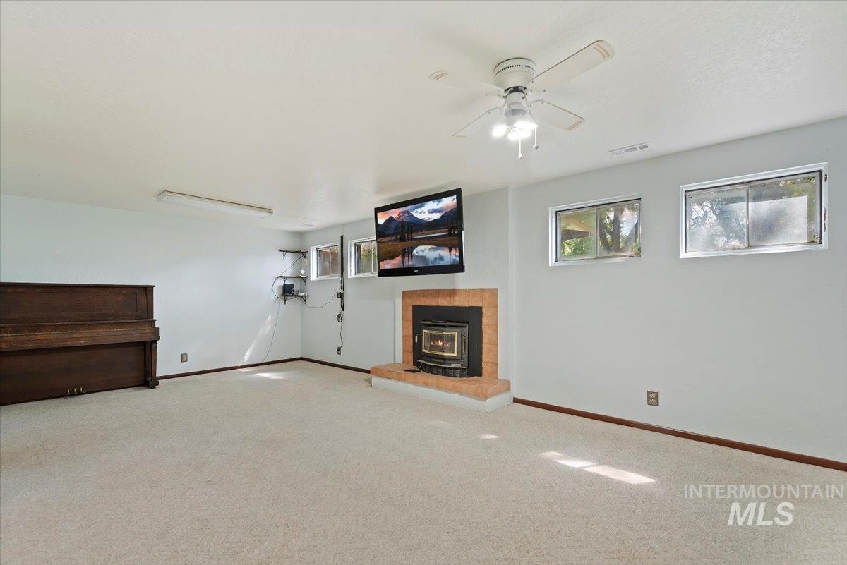 Below grade area featuring a wood stove, carpet floors, and ceiling fan