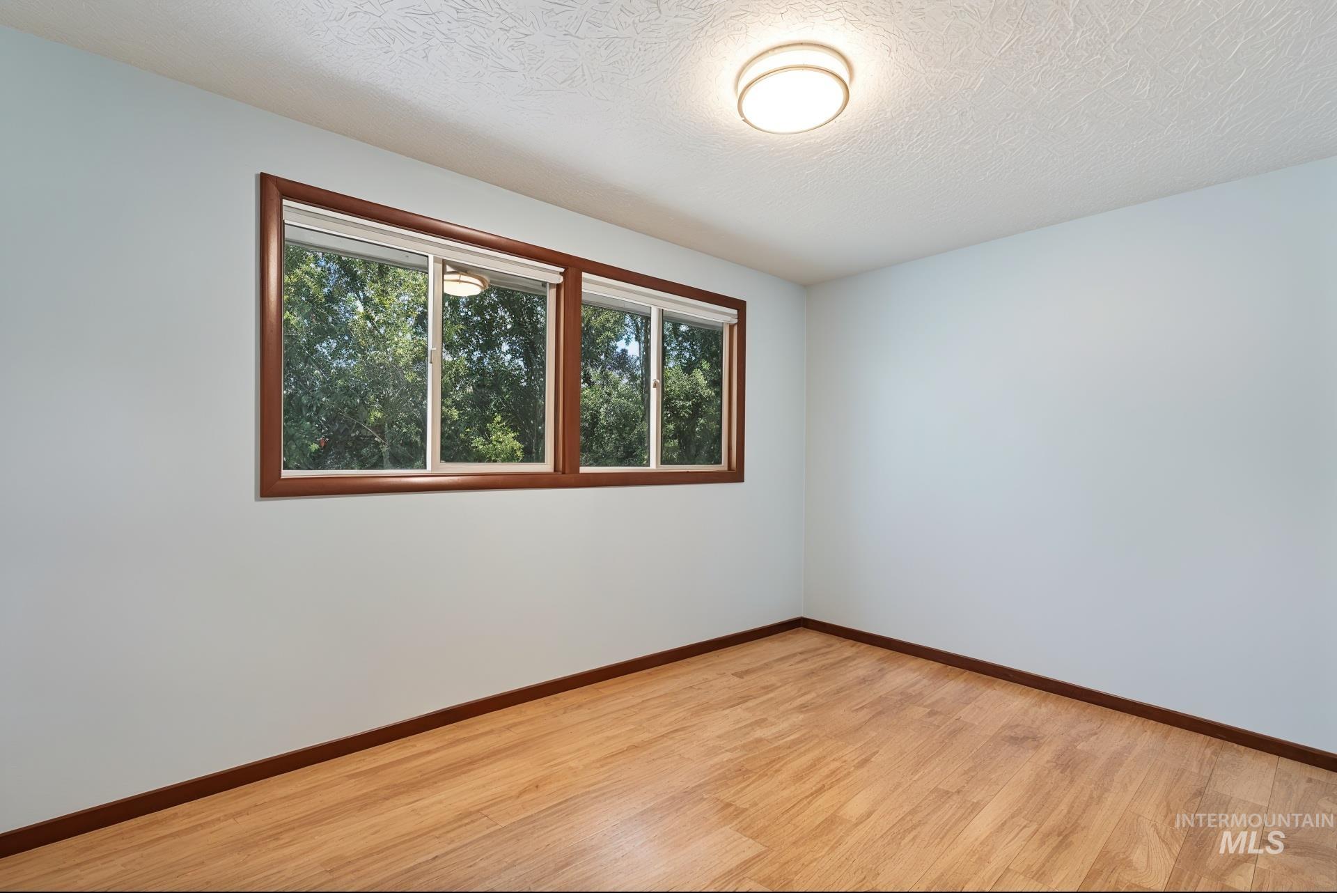 Empty room with light wood-style flooring and a textured ceiling