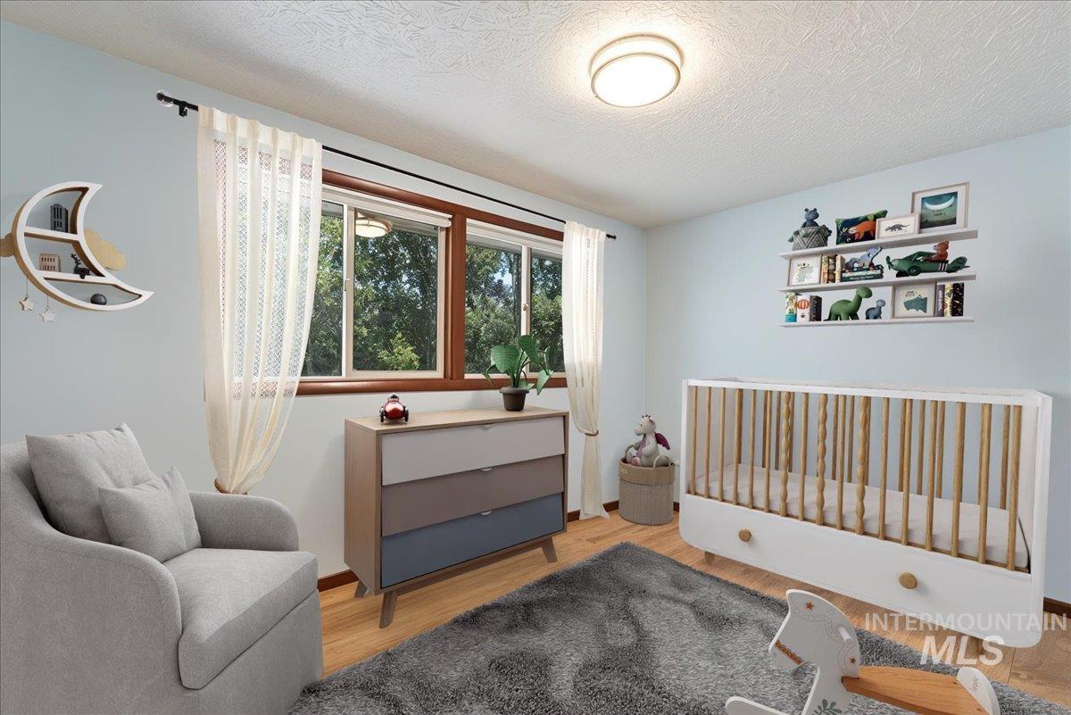 Virtual 3rd Bedroom perfect for a babies room or featuring a crib or a den, a textured ceiling, and wood finished floors