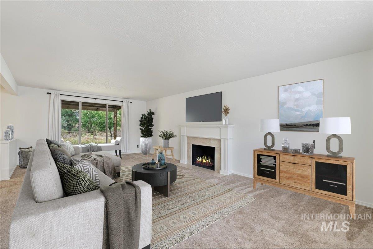 Living area with carpet flooring, a high end fireplace, and a textured ceiling