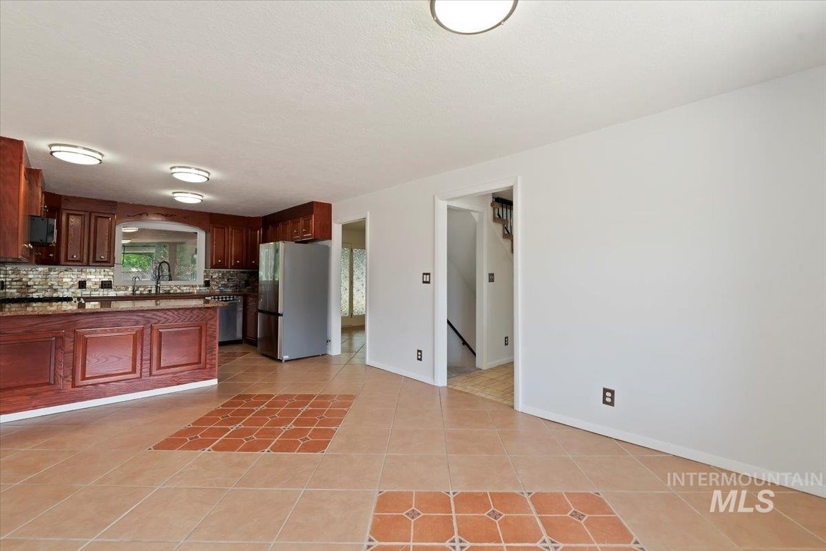 Kitchen with light tile patterned flooring, stainless steel appliances, tasteful backsplash, dark stone countertops, and arched walkways