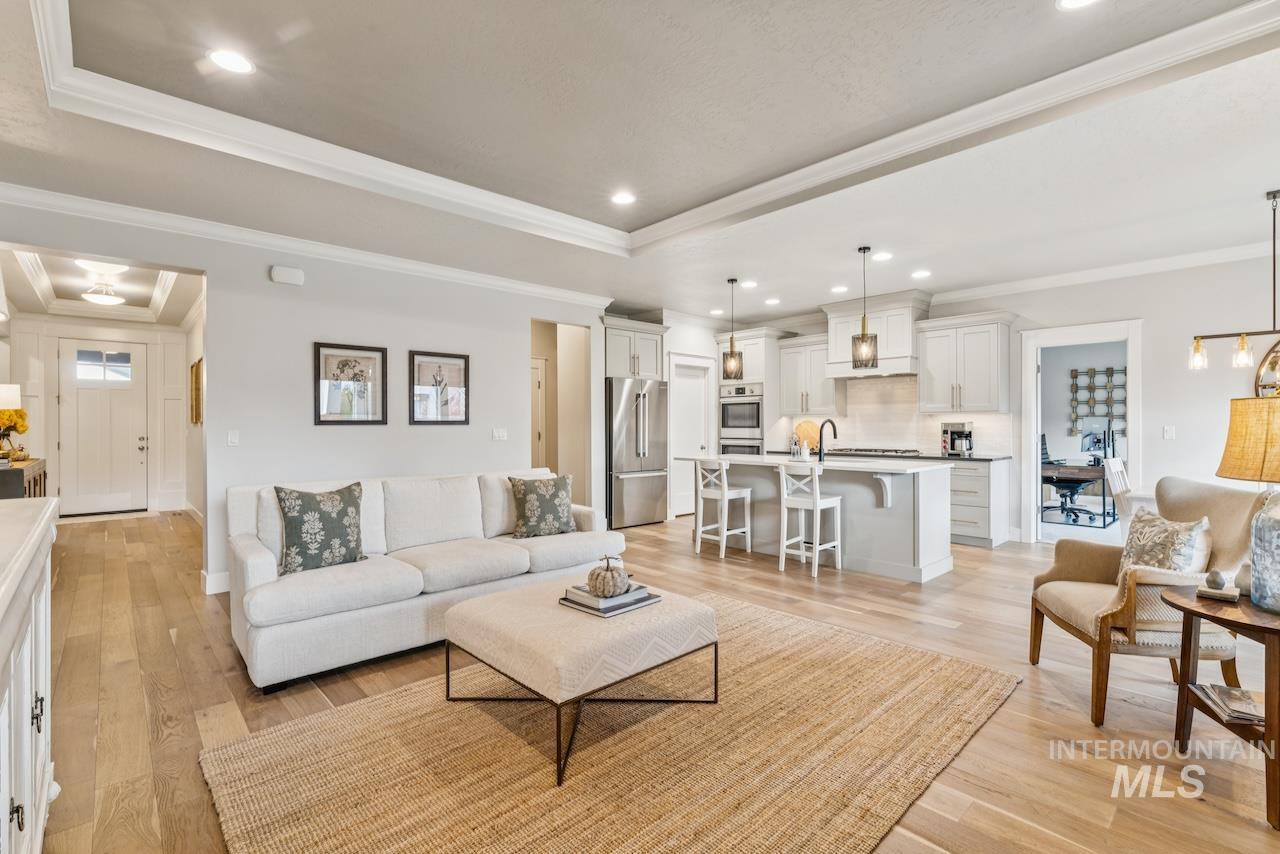 Living room featuring crown molding, recessed lighting, a tray ceiling, light wood finished floors, and a chandelier