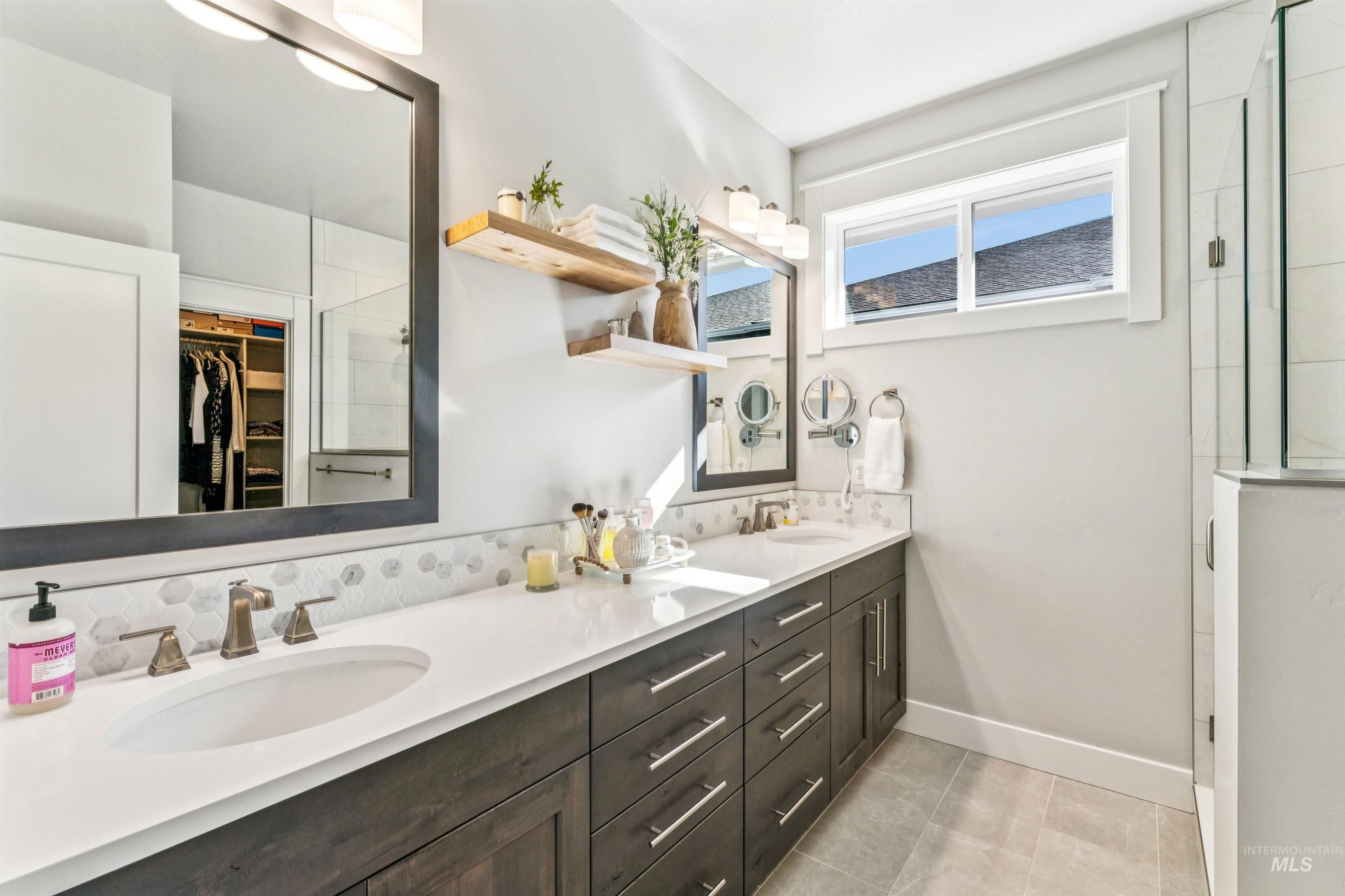 Full bath with double vanity, a walk in closet, healthy amount of natural light, and a shower stall