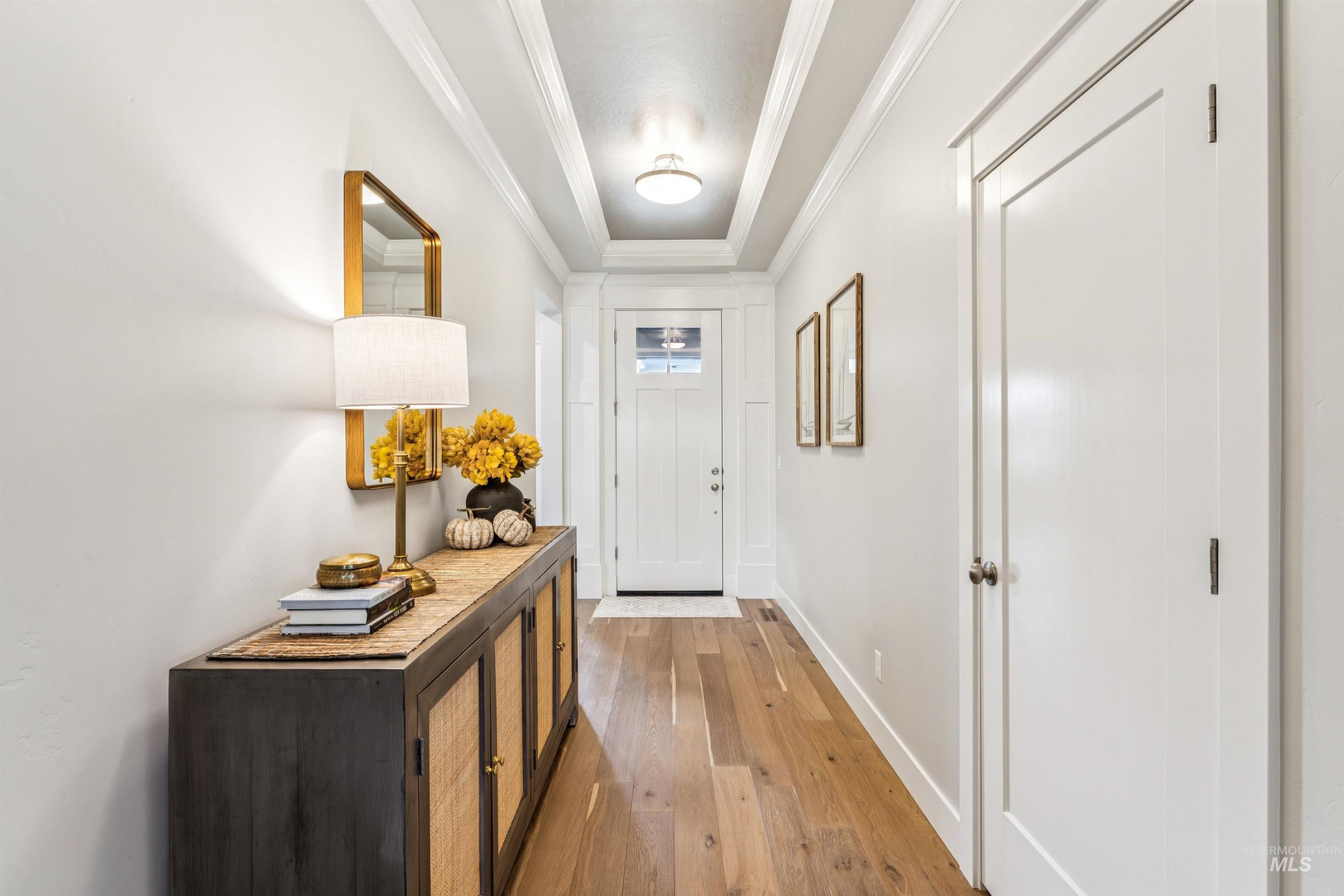 Entryway featuring a tray ceiling, crown molding, and hardwood / wood-style flooring