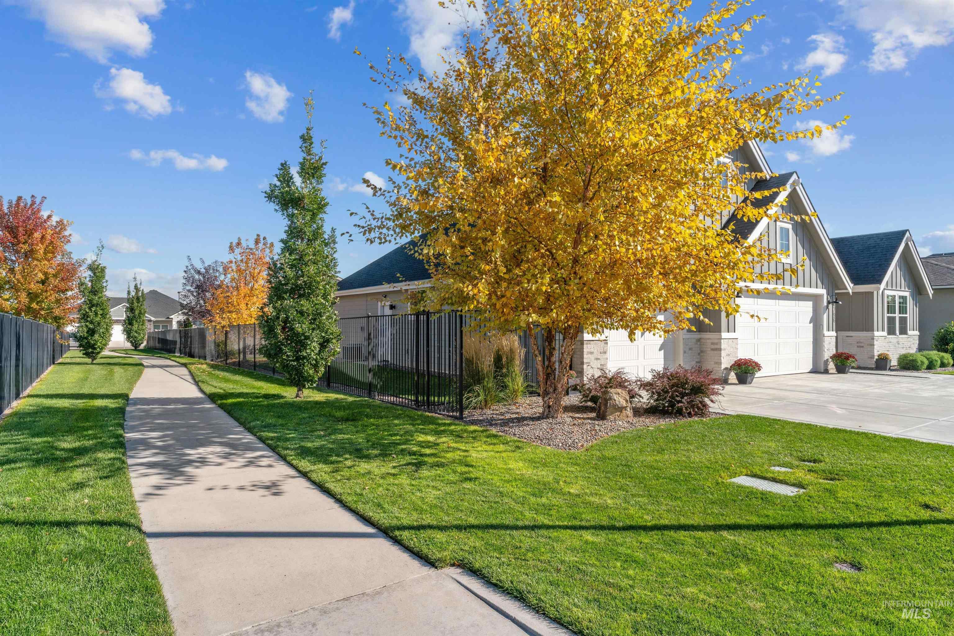 View of property hidden behind natural elements with board and batten siding, concrete driveway, a residential view, and a garage