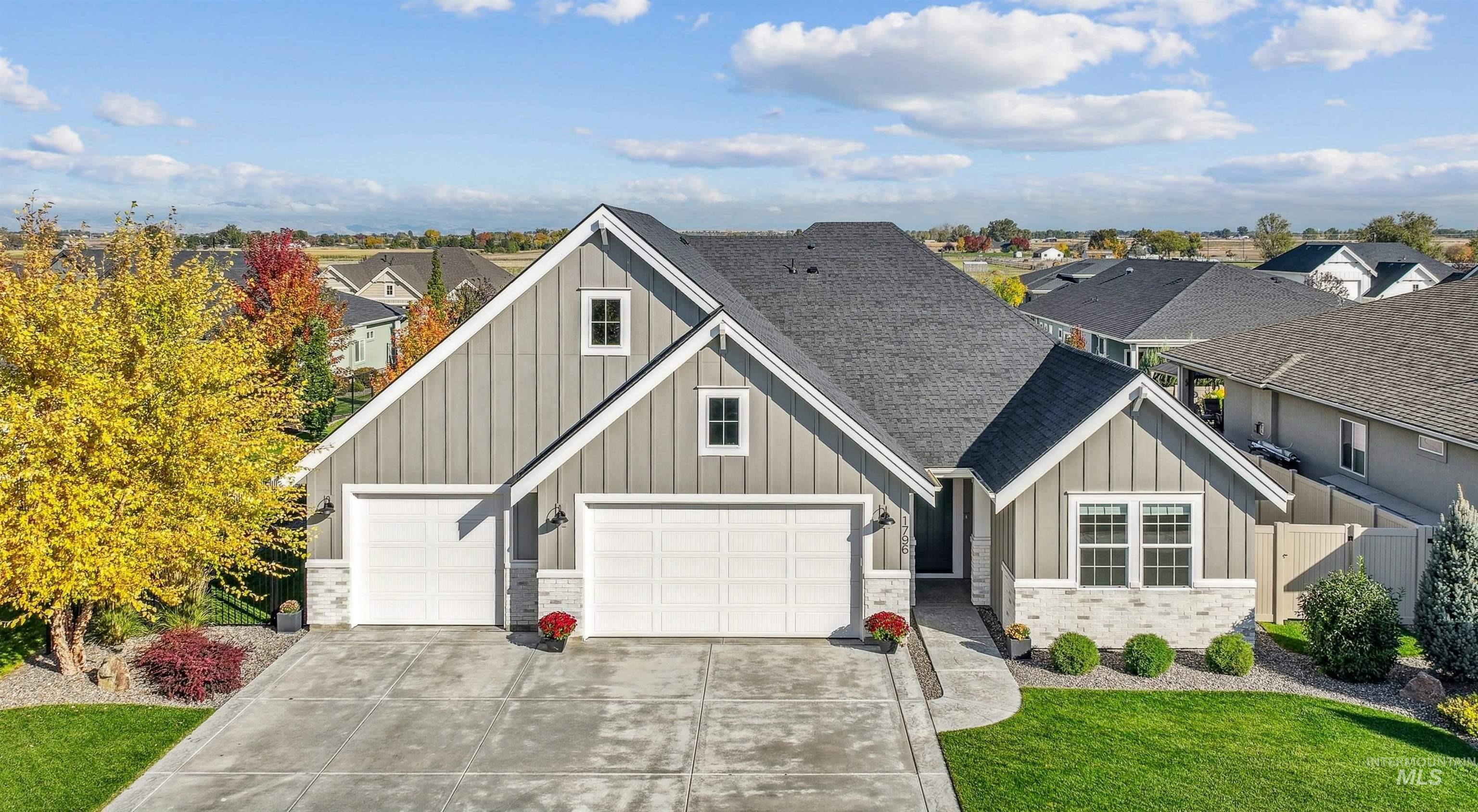 View of front of property featuring board and batten siding, roof with shingles, driveway, and a garage