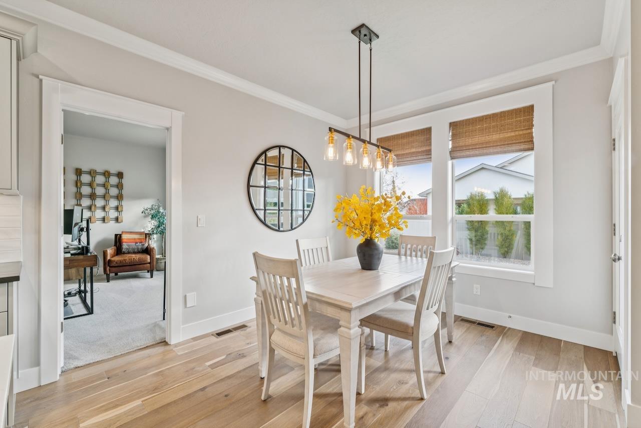 Dining space featuring ornamental molding, light wood-style floors, and a desk