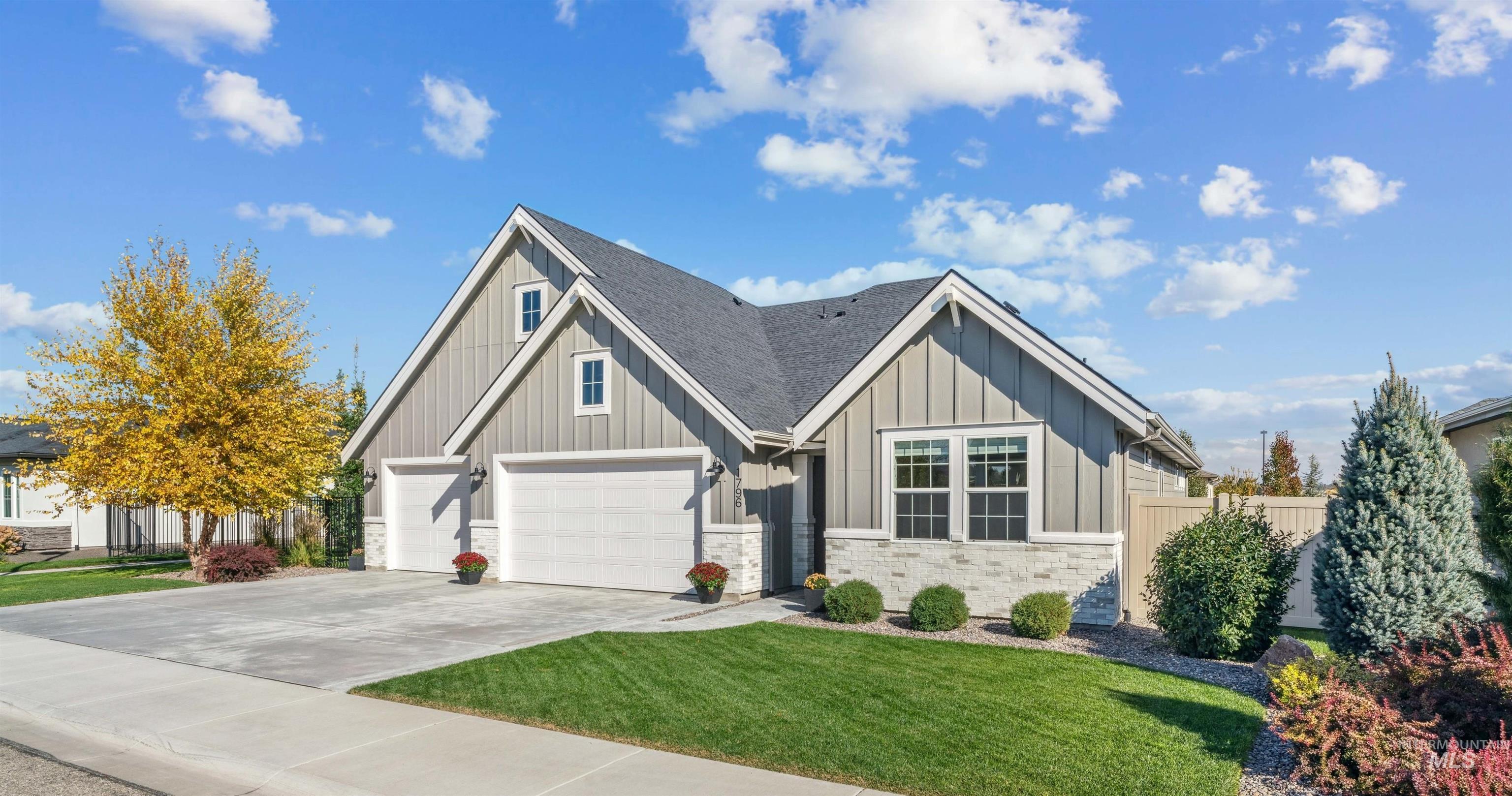 View of front of property featuring board and batten siding, driveway, stone siding, and a shingled roof