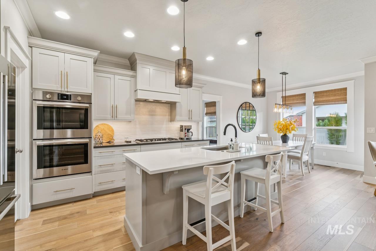 Kitchen featuring stainless steel appliances, ornamental molding, a breakfast bar, white cabinets, and tasteful backsplash