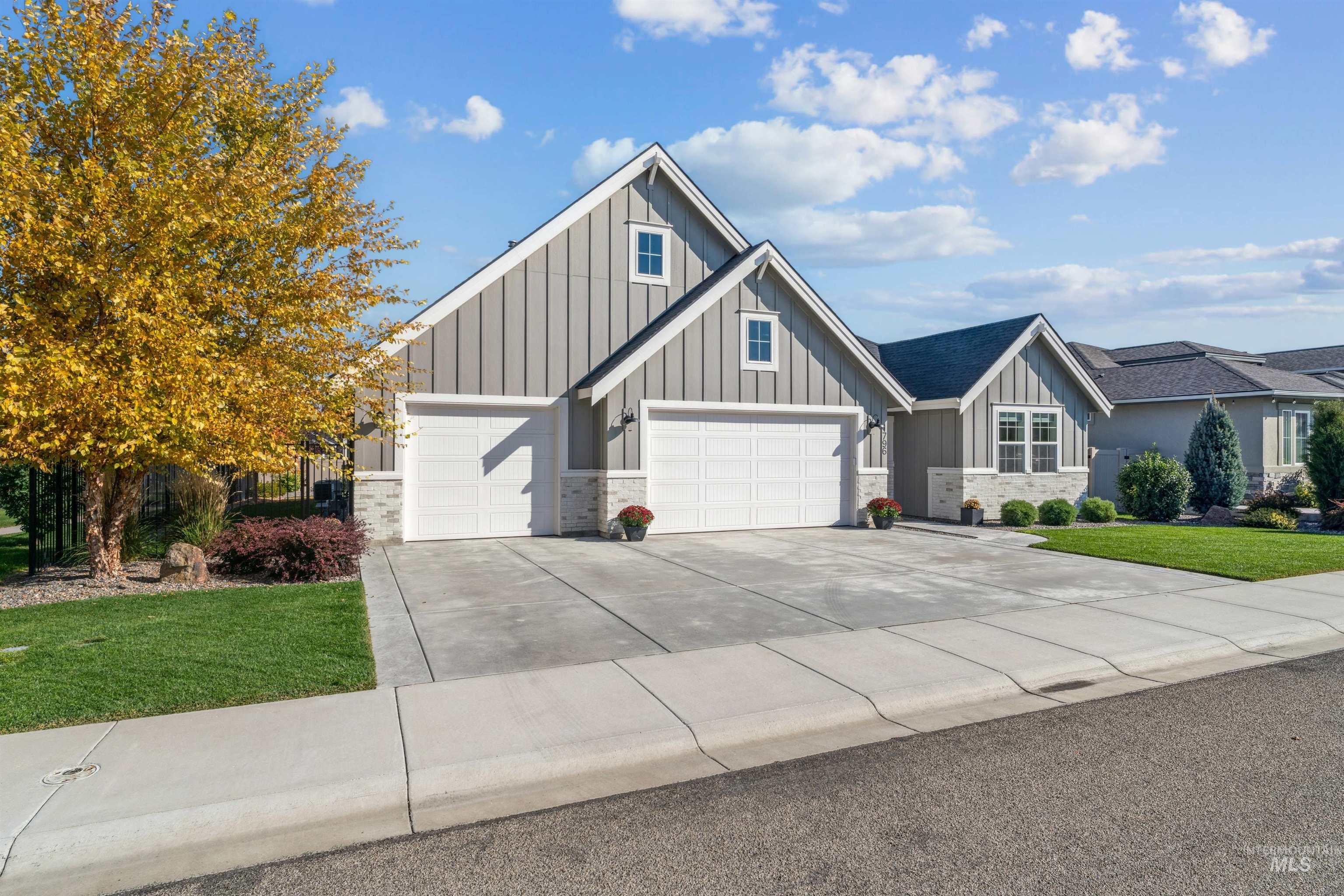 Craftsman-style home featuring board and batten siding, a front lawn, driveway, and stone siding