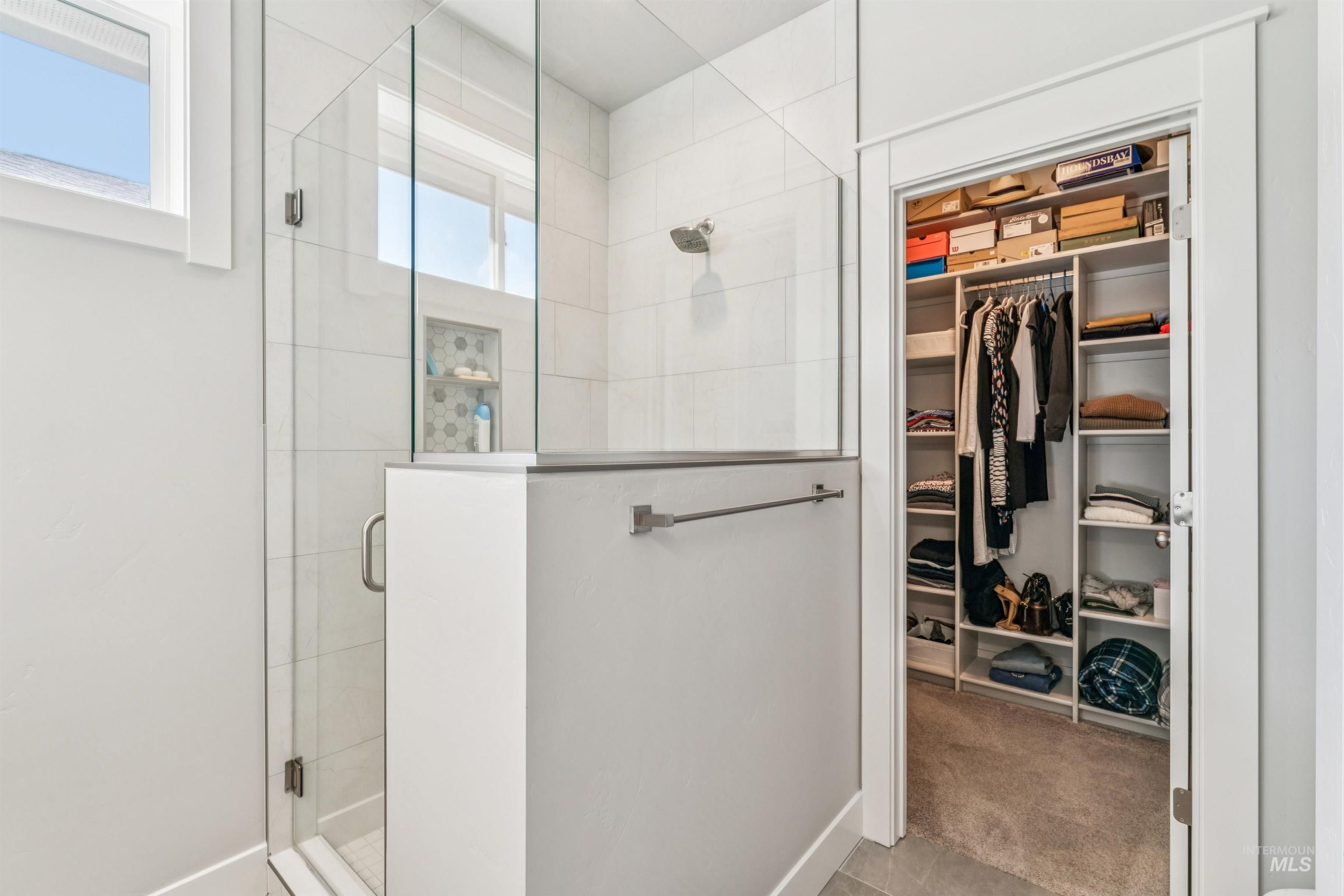 Full bathroom with a shower stall, a walk in closet, and tile patterned floors