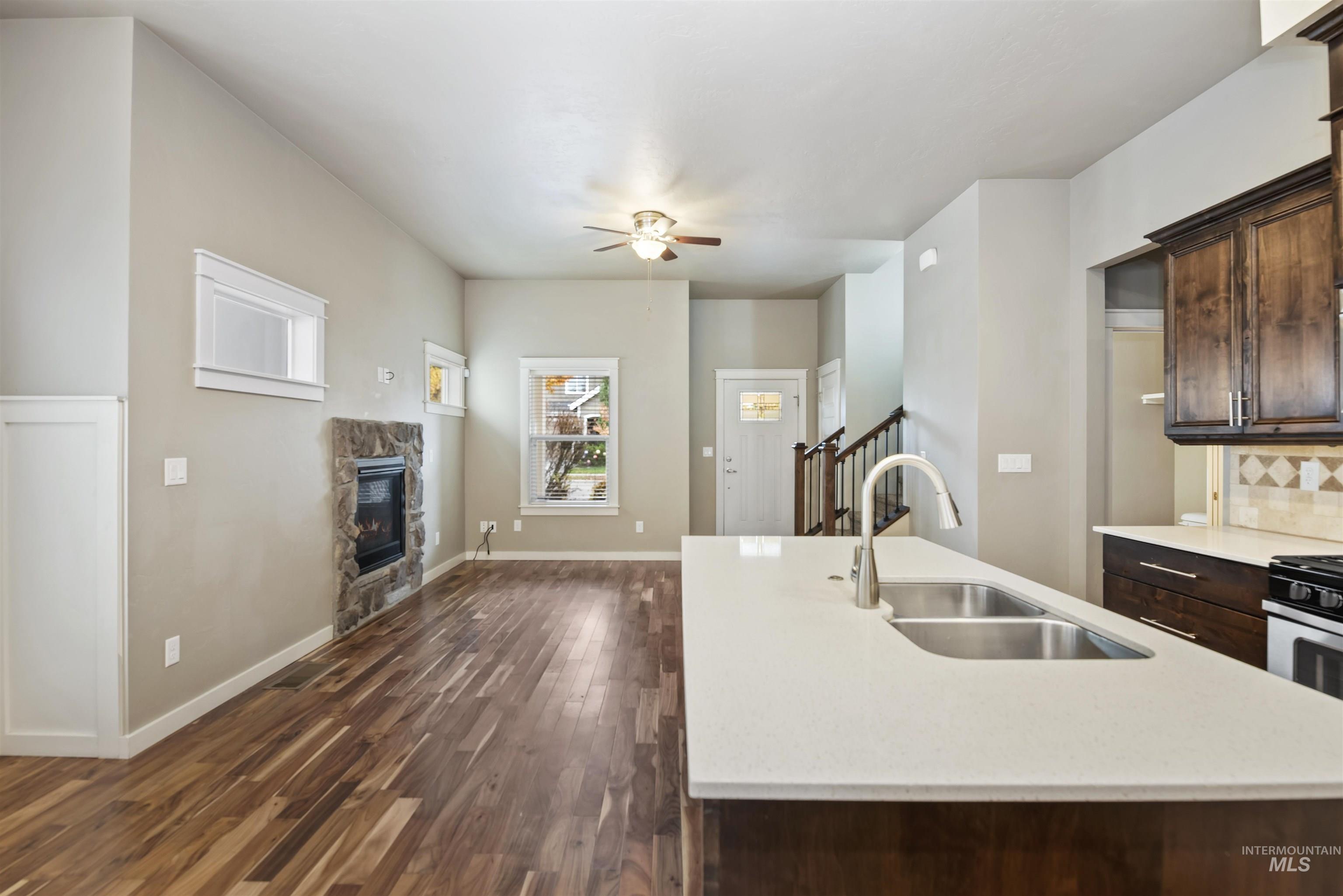 Kitchen with dark brown cabinetry, a kitchen island with sink, dark wood finished floors, and a ceiling fan