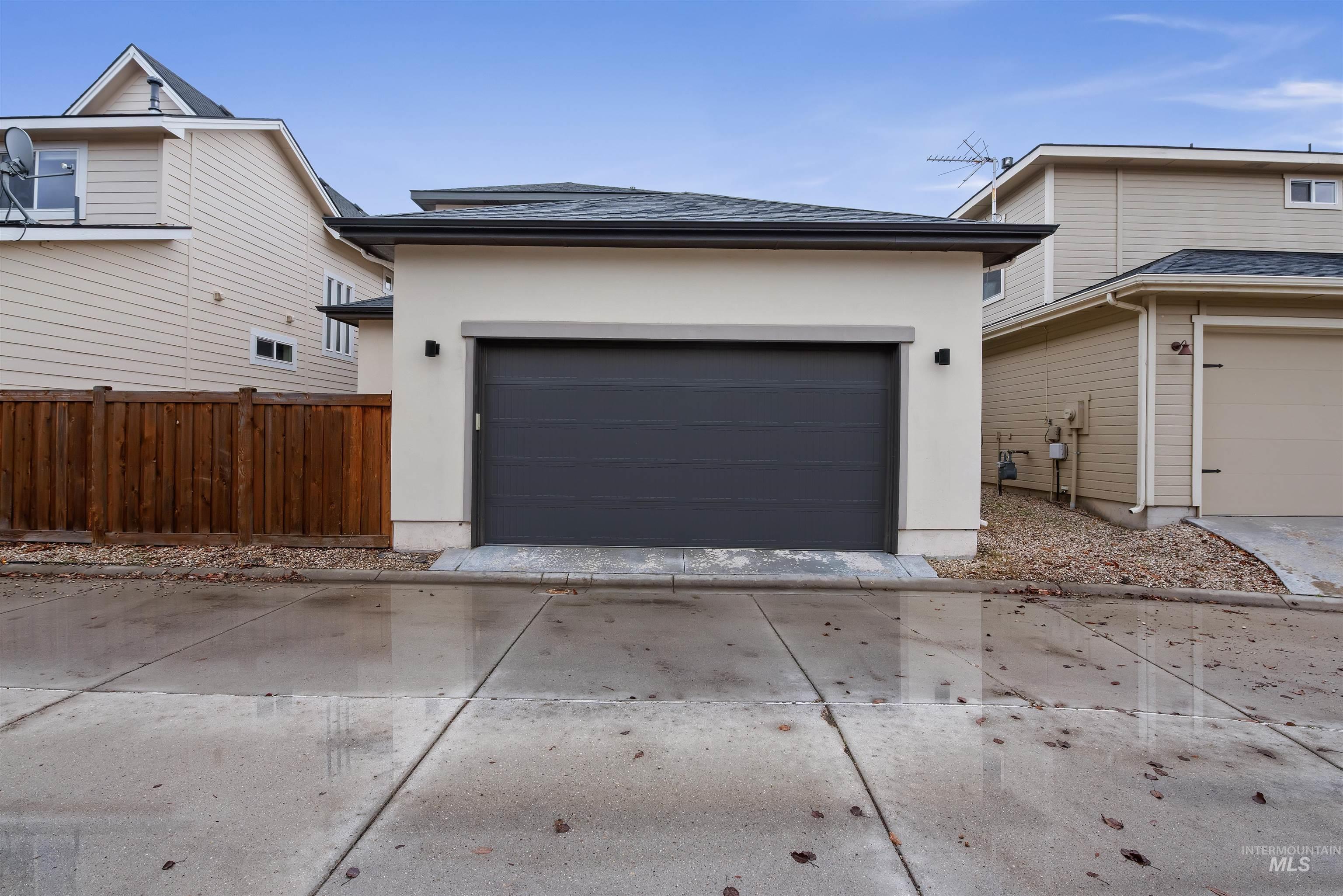 View of front of house with stucco siding, concrete driveway, and roof with shingles