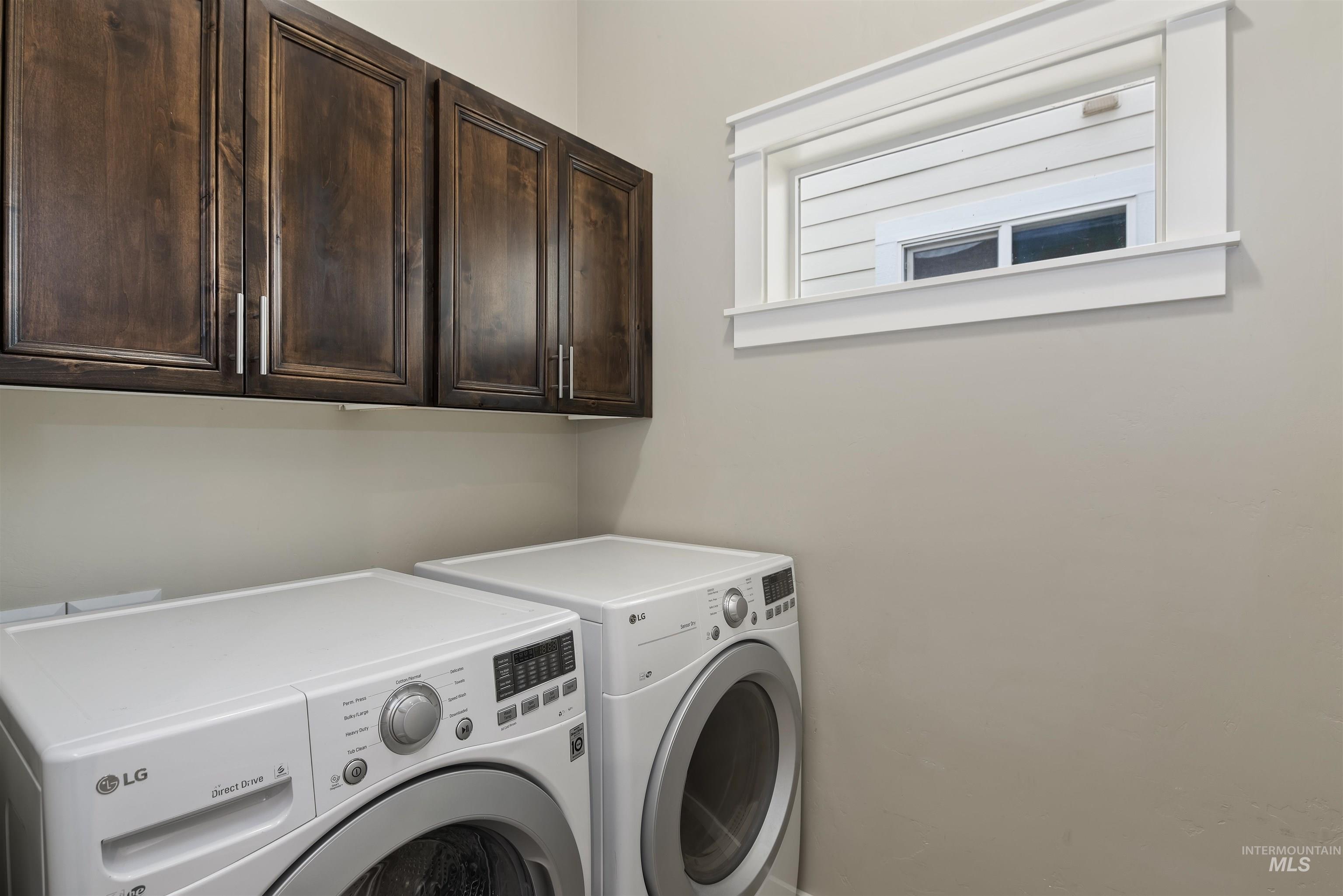 Laundry area featuring separate washer and dryer and cabinet space