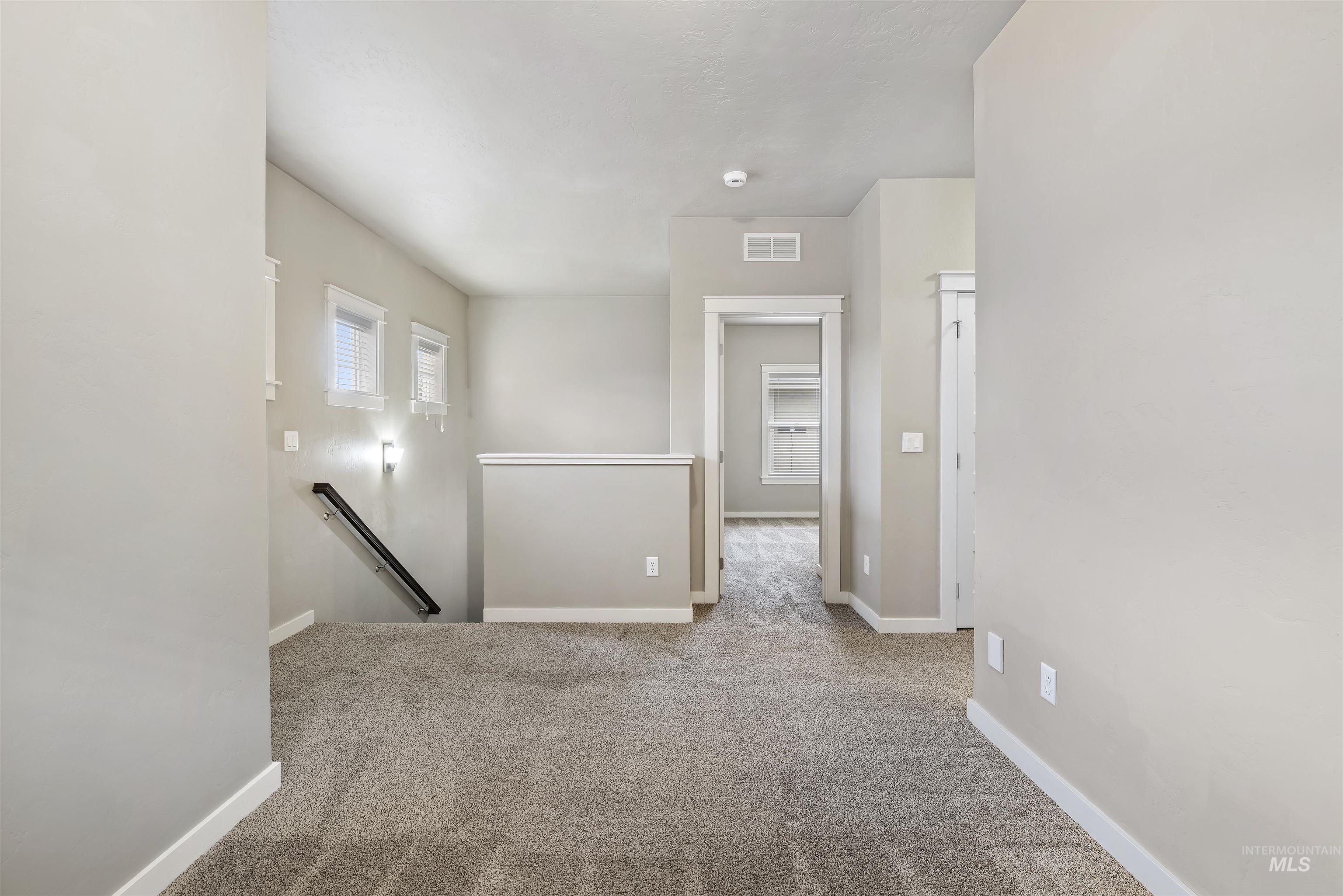 Carpeted spare room featuring baseboards