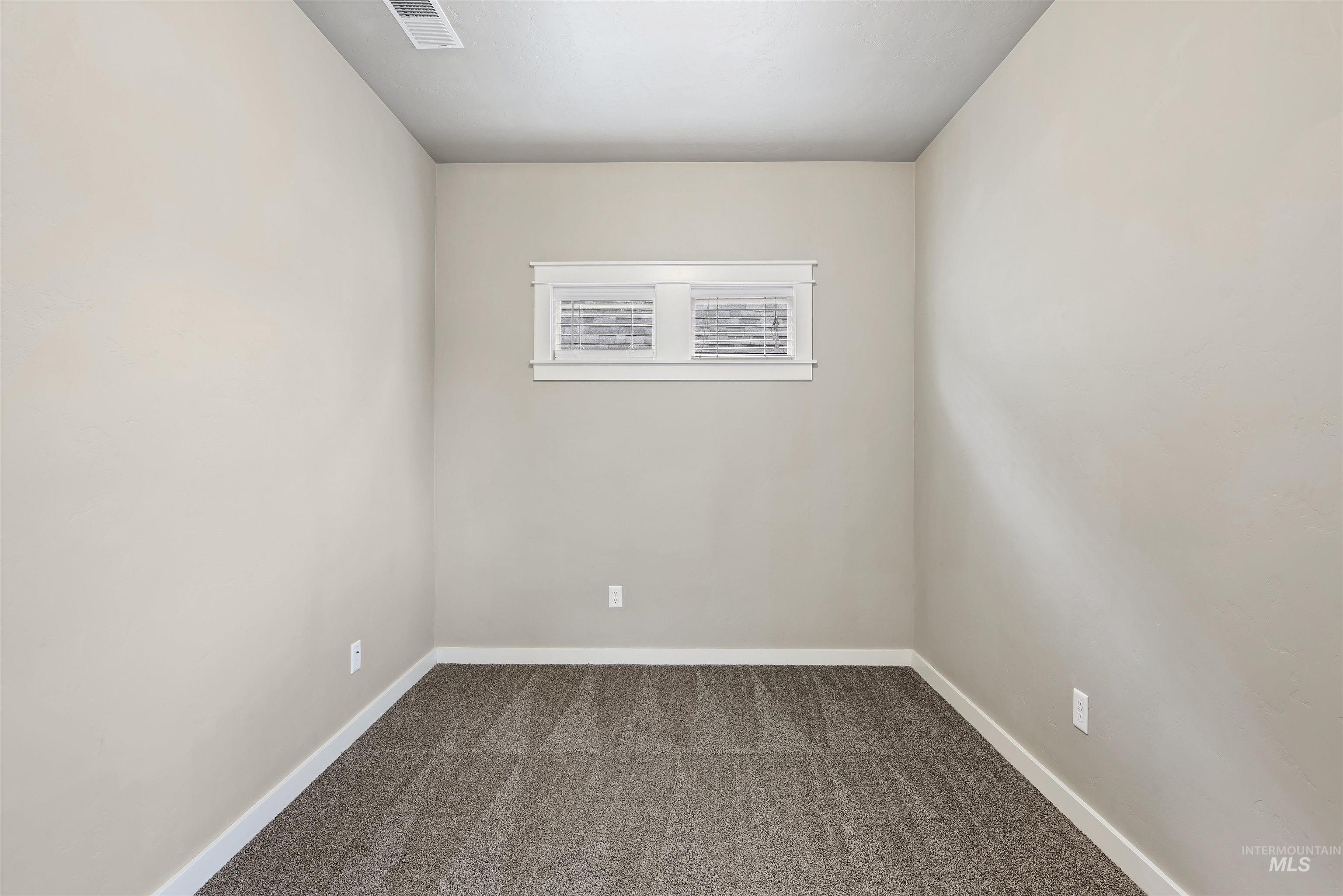Empty room featuring dark carpet and baseboards