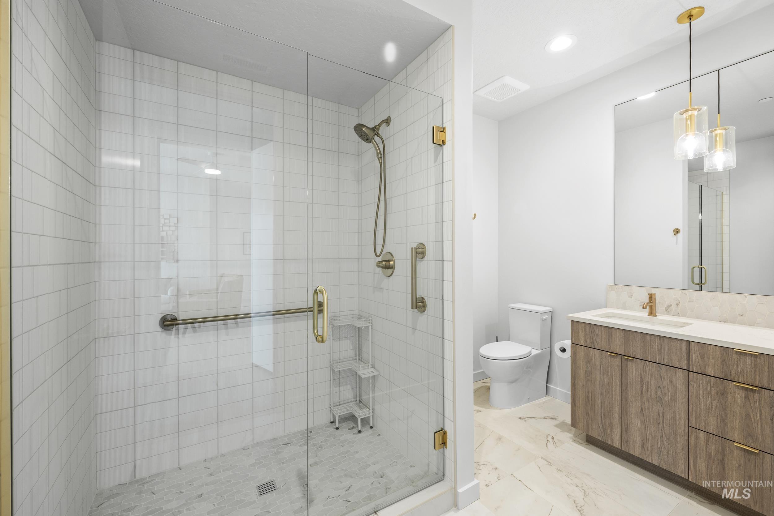 Bathroom with a shower stall, vanity, marble finish flooring, and recessed lighting